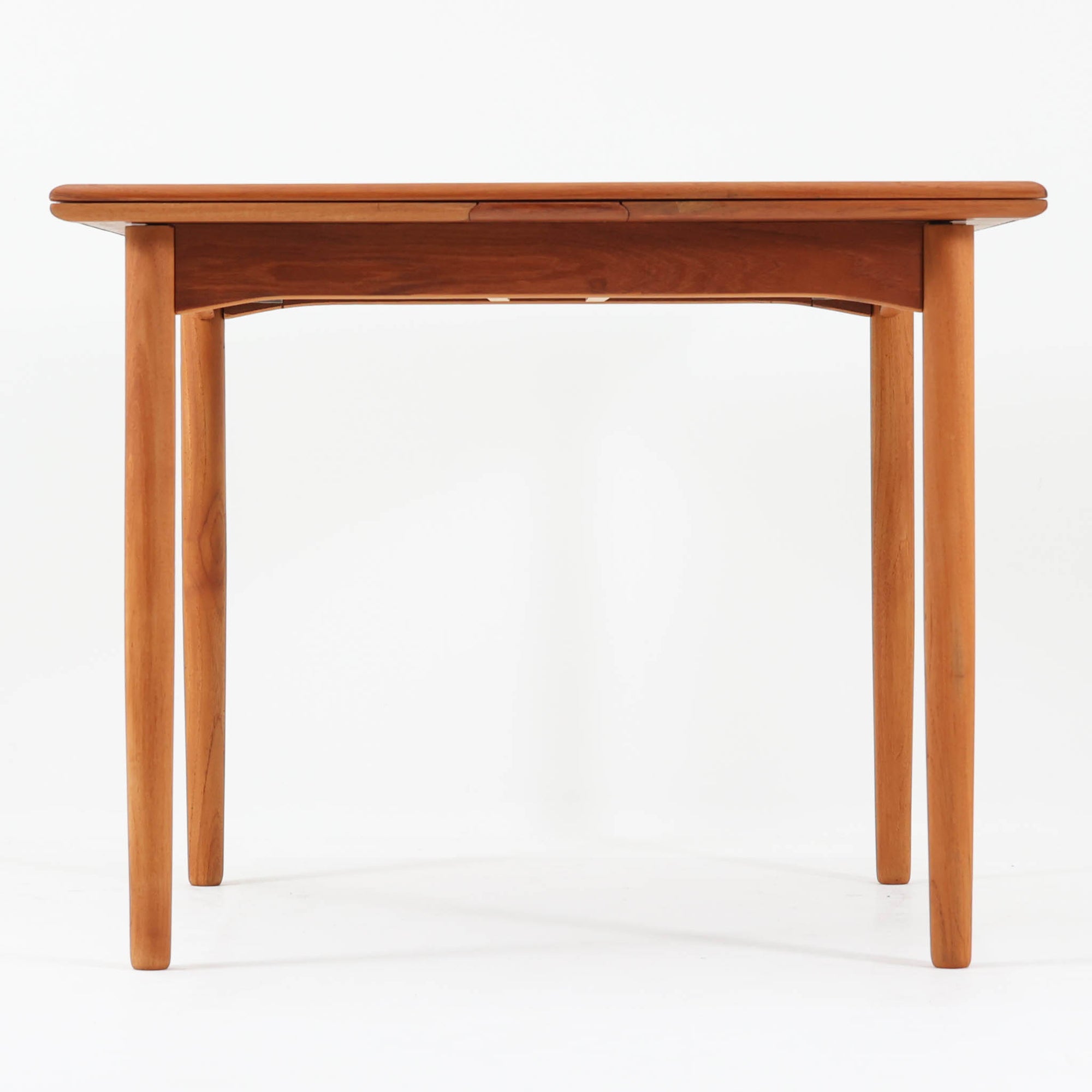 北欧らしい実用性と素材の良さが感じられる正方形エクステンションテーブルです。天板には良質なチーク材が用いられ、赤みのある木目と滑らかな手触りが、経年変化による深みとともに味わいを増しています。通常時はコンパクトなサイズ感で使いやすく、左右の補助天板を引き出すことで来客時や食事人数に応じて柔軟に対応できる構造です。脚部は細身で圧迫感がなく、幕板の緩やかな曲線が全体にやわらかな印象を与え、ダイニングはもちろんワークテーブルとしてもおすすめです。