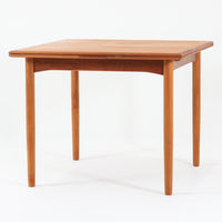 北欧らしい実用性と素材の良さが感じられる正方形エクステンションテーブルです。天板には良質なチーク材が用いられ、赤みのある木目と滑らかな手触りが、経年変化による深みとともに味わいを増しています。通常時はコンパクトなサイズ感で使いやすく、左右の補助天板を引き出すことで来客時や食事人数に応じて柔軟に対応できる構造です。脚部は細身で圧迫感がなく、幕板の緩やかな曲線が全体にやわらかな印象を与え、ダイニングはもちろんワークテーブルとしてもおすすめです。