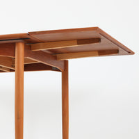 北欧らしい実用性と素材の良さが感じられる正方形エクステンションテーブルです。天板には良質なチーク材が用いられ、赤みのある木目と滑らかな手触りが、経年変化による深みとともに味わいを増しています。通常時はコンパクトなサイズ感で使いやすく、左右の補助天板を引き出すことで来客時や食事人数に応じて柔軟に対応できる構造です。脚部は細身で圧迫感がなく、幕板の緩やかな曲線が全体にやわらかな印象を与え、ダイニングはもちろんワークテーブルとしてもおすすめです。