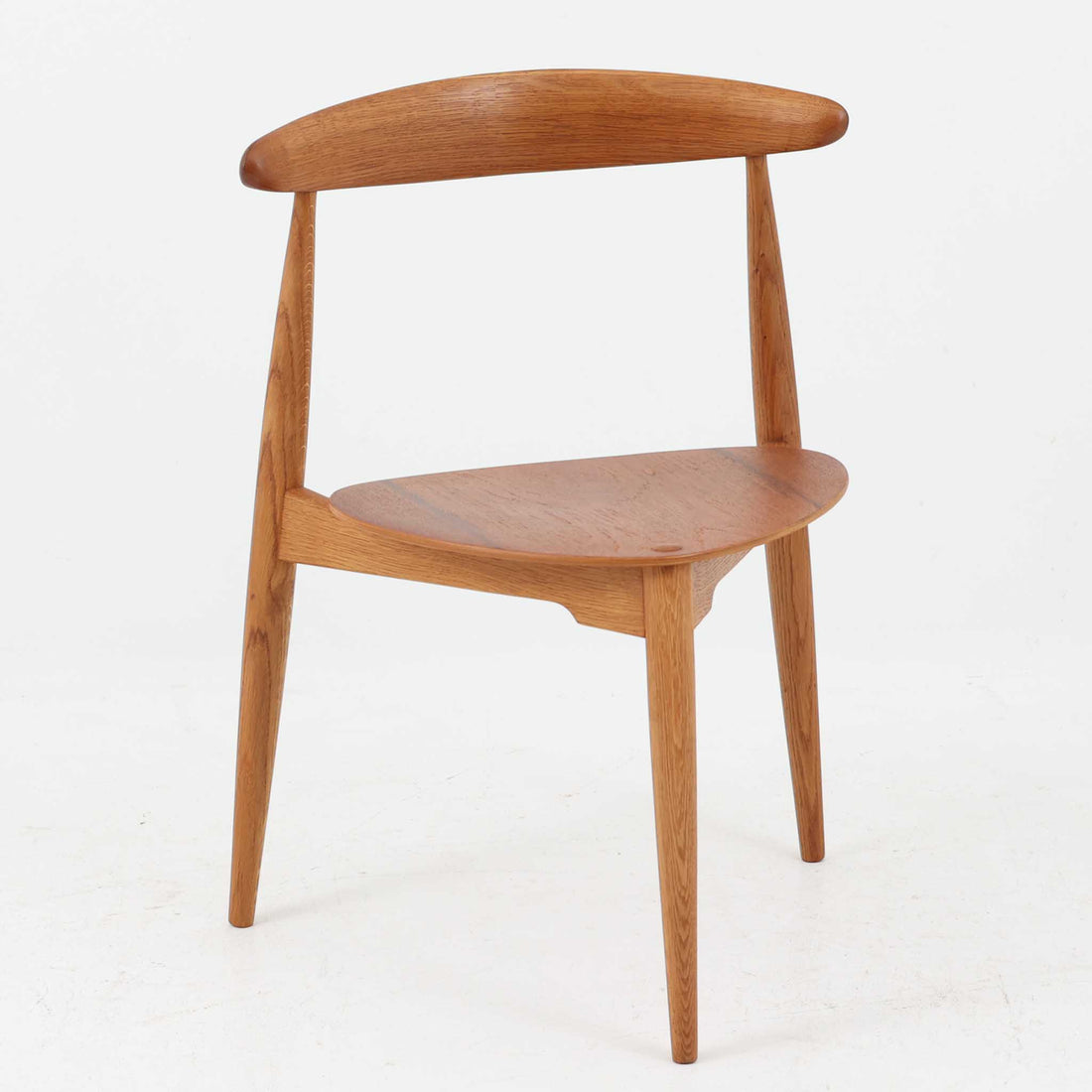 Hans J. Wegnerがデザインし、Fritz Hansen社より発表されたFH4103チェアは、三角形に近い座面と滑らかな曲線を描く笠木が特徴の北欧ビンテージ家具です。フレームには堅牢なオーク材、座面には温かみあるチーク材を組み合わせ、素材のコントラストが美しいバランスを生み出しています。彫刻的なフォルムながら軽やかで実用的な構造は、ダイニングチェアとしてはもちろん、空間のアクセントピースとしても存在感を放ちます。経年による木肌の深い風合いが、ビンテージならではの魅力を引き立てています。