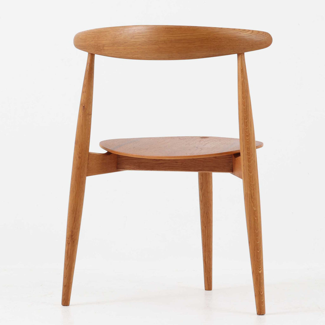 Hans J. Wegnerがデザインし、Fritz Hansen社より発表されたFH4103チェアは、三角形に近い座面と滑らかな曲線を描く笠木が特徴の北欧ビンテージ家具です。フレームには堅牢なオーク材、座面には温かみあるチーク材を組み合わせ、素材のコントラストが美しいバランスを生み出しています。彫刻的なフォルムながら軽やかで実用的な構造は、ダイニングチェアとしてはもちろん、空間のアクセントピースとしても存在感を放ちます。経年による木肌の深い風合いが、ビンテージならではの魅力を引き立てています。
