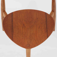 Hans J. Wegnerがデザインし、Fritz Hansen社より発表されたFH4103チェアは、三角形に近い座面と滑らかな曲線を描く笠木が特徴の北欧ビンテージ家具です。フレームには堅牢なオーク材、座面には温かみあるチーク材を組み合わせ、素材のコントラストが美しいバランスを生み出しています。彫刻的なフォルムながら軽やかで実用的な構造は、ダイニングチェアとしてはもちろん、空間のアクセントピースとしても存在感を放ちます。経年による木肌の深い風合いが、ビンテージならではの魅力を引き立てています。
