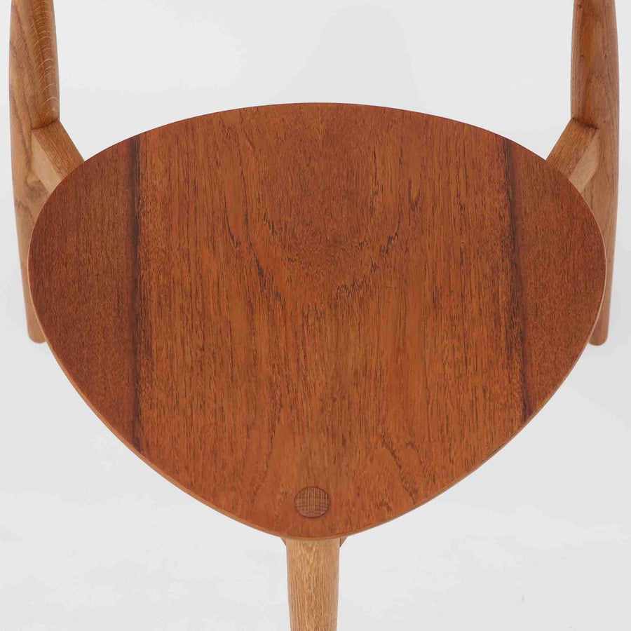 Hans J. Wegnerがデザインし、Fritz Hansen社より発表されたFH4103チェアは、三角形に近い座面と滑らかな曲線を描く笠木が特徴の北欧ビンテージ家具です。フレームには堅牢なオーク材、座面には温かみあるチーク材を組み合わせ、素材のコントラストが美しいバランスを生み出しています。彫刻的なフォルムながら軽やかで実用的な構造は、ダイニングチェアとしてはもちろん、空間のアクセントピースとしても存在感を放ちます。経年による木肌の深い風合いが、ビンテージならではの魅力を引き立てています。