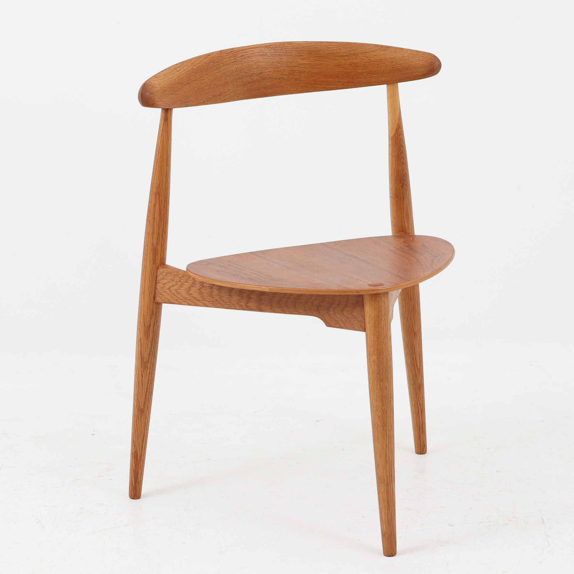Hans J. Wegnerがデザインし、Fritz Hansen社より発表されたFH4103チェアは、三角形に近い座面と滑らかな曲線を描く笠木が特徴の北欧ビンテージ家具です。フレームには堅牢なオーク材、座面には温かみあるチーク材を組み合わせ、素材のコントラストが美しいバランスを生み出しています。彫刻的なフォルムながら軽やかで実用的な構造は、ダイニングチェアとしてはもちろん、空間のアクセントピースとしても存在感を放ちます。経年による木肌の深い風合いが、ビンテージならではの魅力を引き立てています。