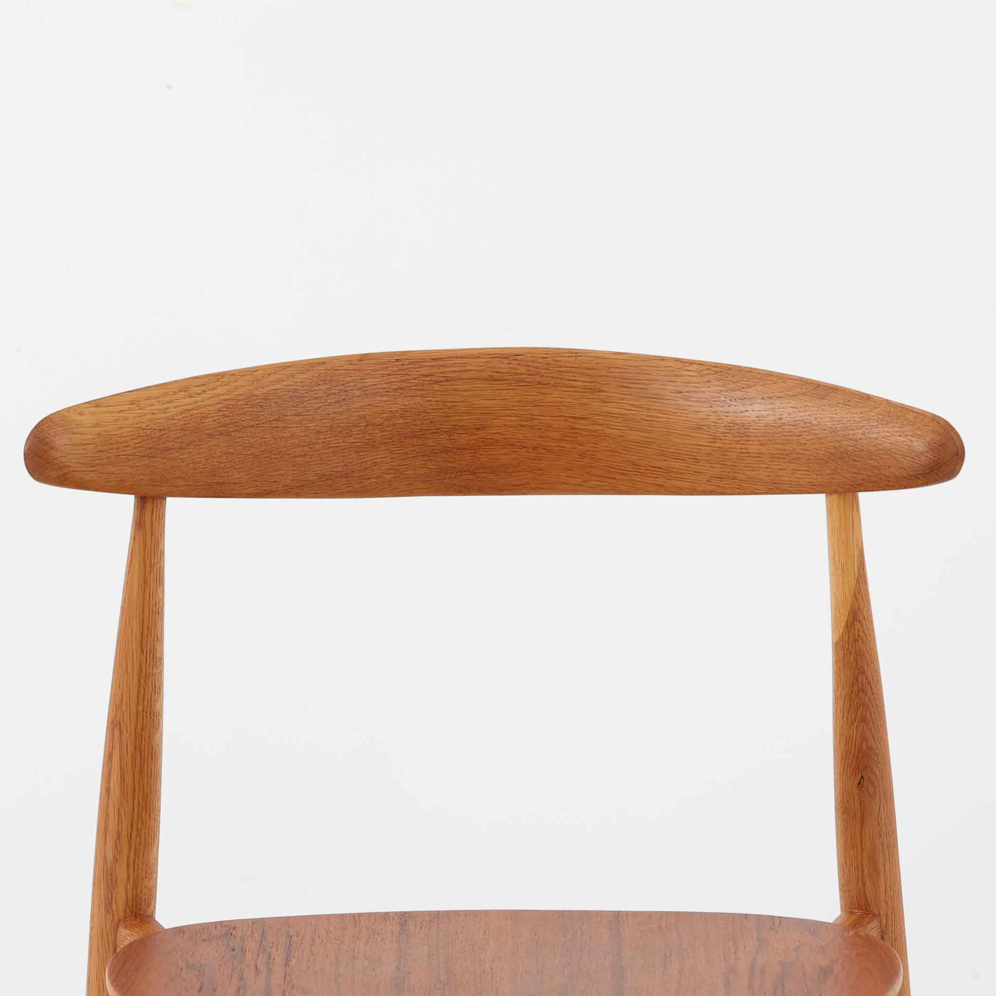 Hans J. Wegnerがデザインし、Fritz Hansen社より発表されたFH4103チェアは、三角形に近い座面と滑らかな曲線を描く笠木が特徴の北欧ビンテージ家具です。フレームには堅牢なオーク材、座面には温かみあるチーク材を組み合わせ、素材のコントラストが美しいバランスを生み出しています。彫刻的なフォルムながら軽やかで実用的な構造は、ダイニングチェアとしてはもちろん、空間のアクセントピースとしても存在感を放ちます。経年による木肌の深い風合いが、ビンテージならではの魅力を引き立てています。