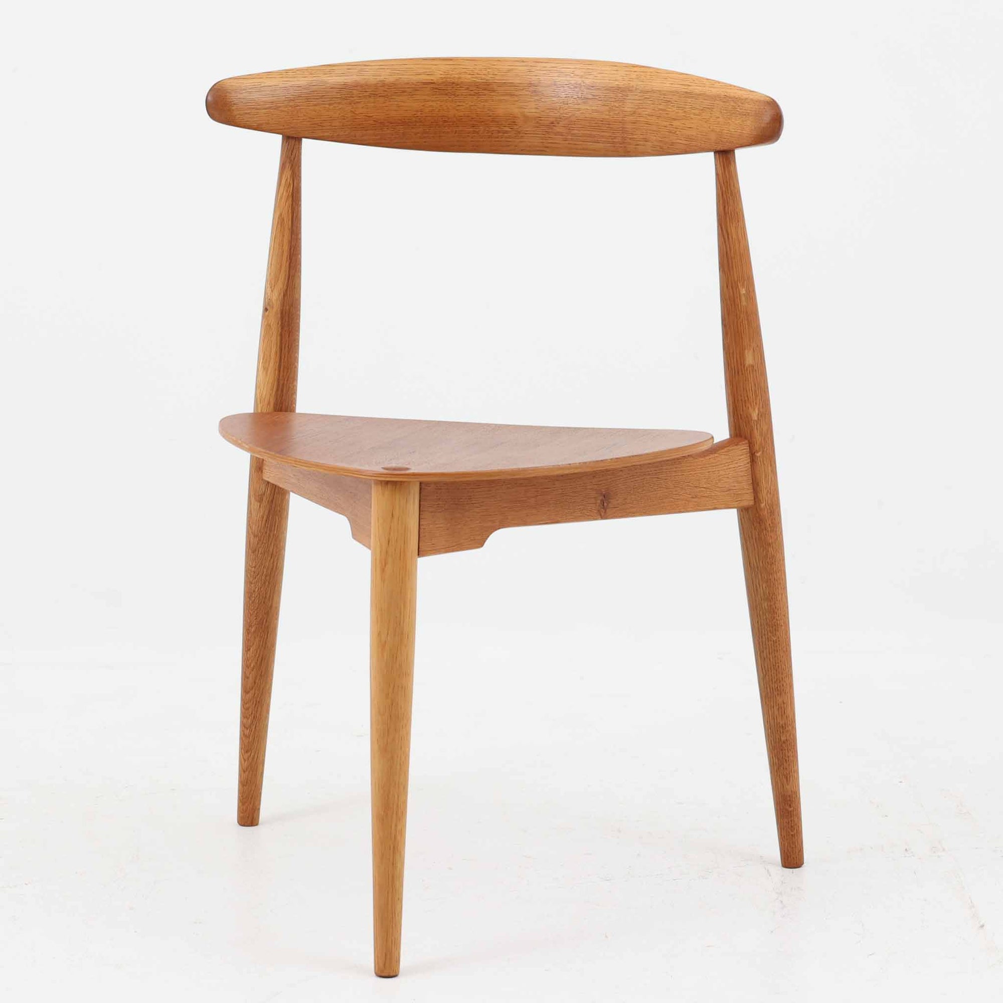 Hans J. Wegnerがデザインし、Fritz Hansen社より発表されたFH4103チェアは、三角形に近い座面と滑らかな曲線を描く笠木が特徴の北欧ビンテージ家具です。フレームには堅牢なオーク材、座面には温かみあるチーク材を組み合わせ、素材のコントラストが美しいバランスを生み出しています。彫刻的なフォルムながら軽やかで実用的な構造は、ダイニングチェアとしてはもちろん、空間のアクセントピースとしても存在感を放ちます。経年による木肌の深い風合いが、ビンテージならではの魅力を引き立てています。