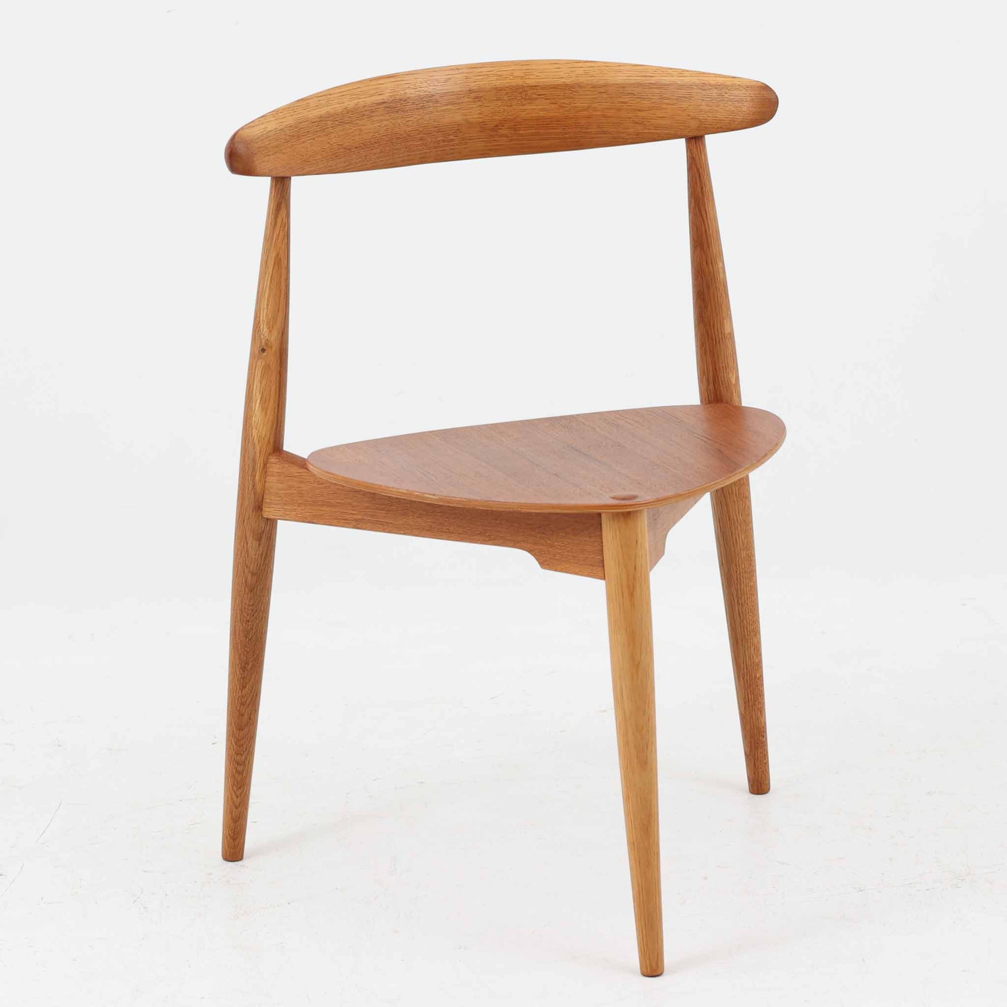 Hans J. Wegnerがデザインし、Fritz Hansen社より発表されたFH4103チェアは、三角形に近い座面と滑らかな曲線を描く笠木が特徴の北欧ビンテージ家具です。フレームには堅牢なオーク材、座面には温かみあるチーク材を組み合わせ、素材のコントラストが美しいバランスを生み出しています。彫刻的なフォルムながら軽やかで実用的な構造は、ダイニングチェアとしてはもちろん、空間のアクセントピースとしても存在感を放ちます。経年による木肌の深い風合いが、ビンテージならではの魅力を引き立てています。