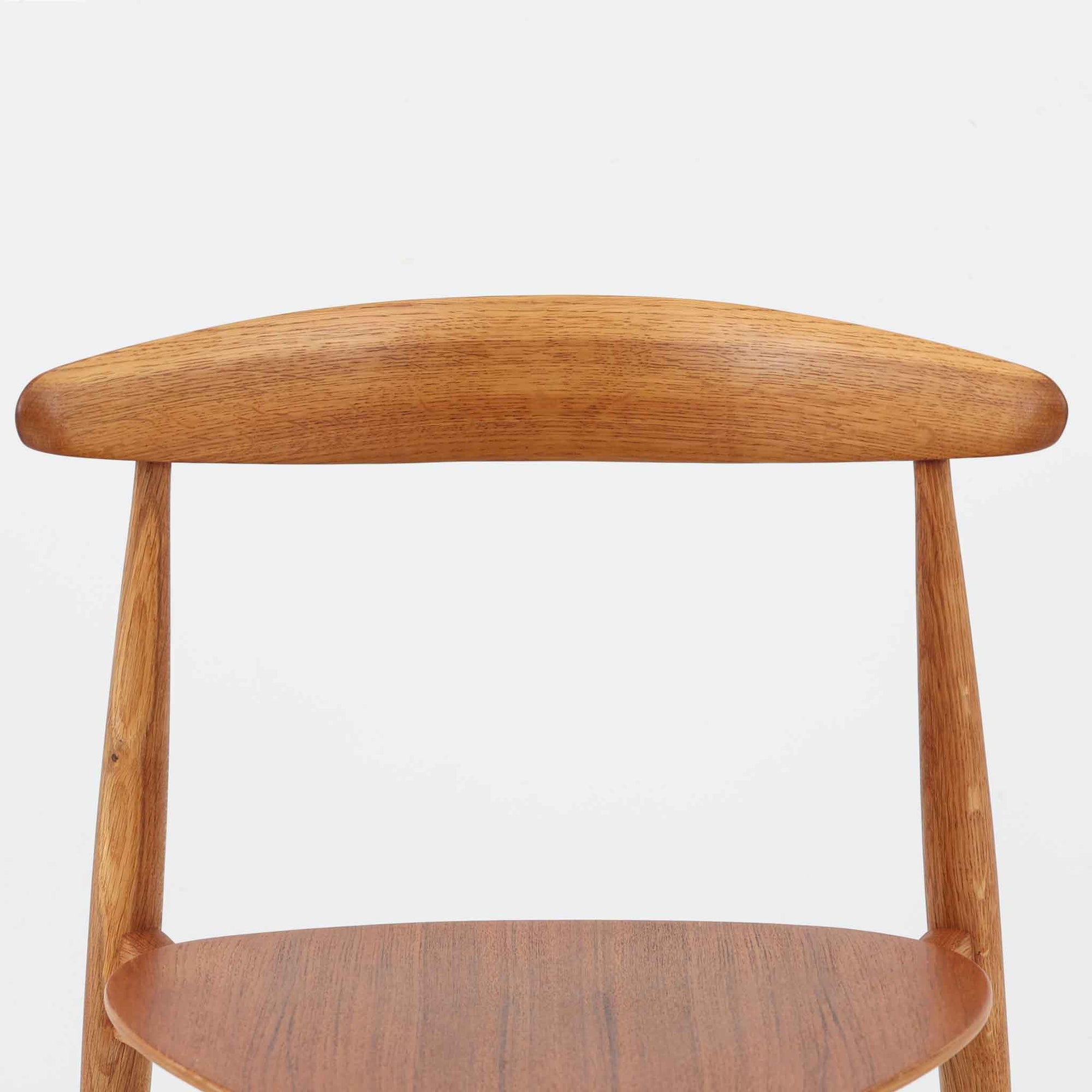 Hans J. Wegnerがデザインし、Fritz Hansen社より発表されたFH4103チェアは、三角形に近い座面と滑らかな曲線を描く笠木が特徴の北欧ビンテージ家具です。フレームには堅牢なオーク材、座面には温かみあるチーク材を組み合わせ、素材のコントラストが美しいバランスを生み出しています。彫刻的なフォルムながら軽やかで実用的な構造は、ダイニングチェアとしてはもちろん、空間のアクセントピースとしても存在感を放ちます。経年による木肌の深い風合いが、ビンテージならではの魅力を引き立てています。