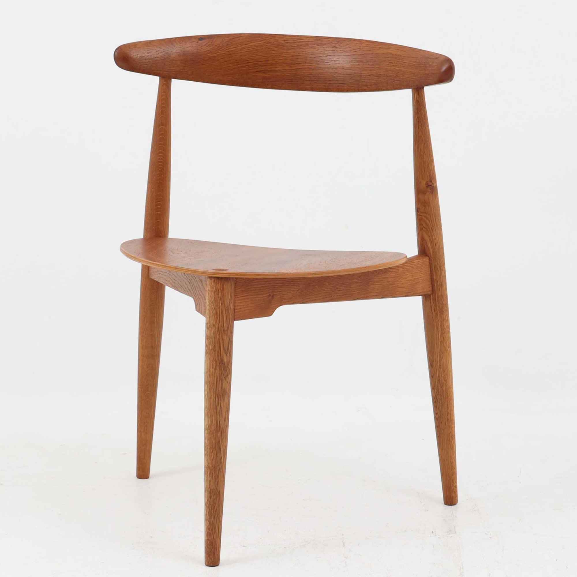 Hans J. Wegnerがデザインし、Fritz Hansen社より発表されたFH4103チェアは、三角形に近い座面と滑らかな曲線を描く笠木が特徴の北欧ビンテージ家具です。フレームには堅牢なオーク材、座面には温かみあるチーク材を組み合わせ、素材のコントラストが美しいバランスを生み出しています。彫刻的なフォルムながら軽やかで実用的な構造は、ダイニングチェアとしてはもちろん、空間のアクセントピースとしても存在感を放ちます。経年による木肌の深い風合いが、ビンテージならではの魅力を引き立てています。