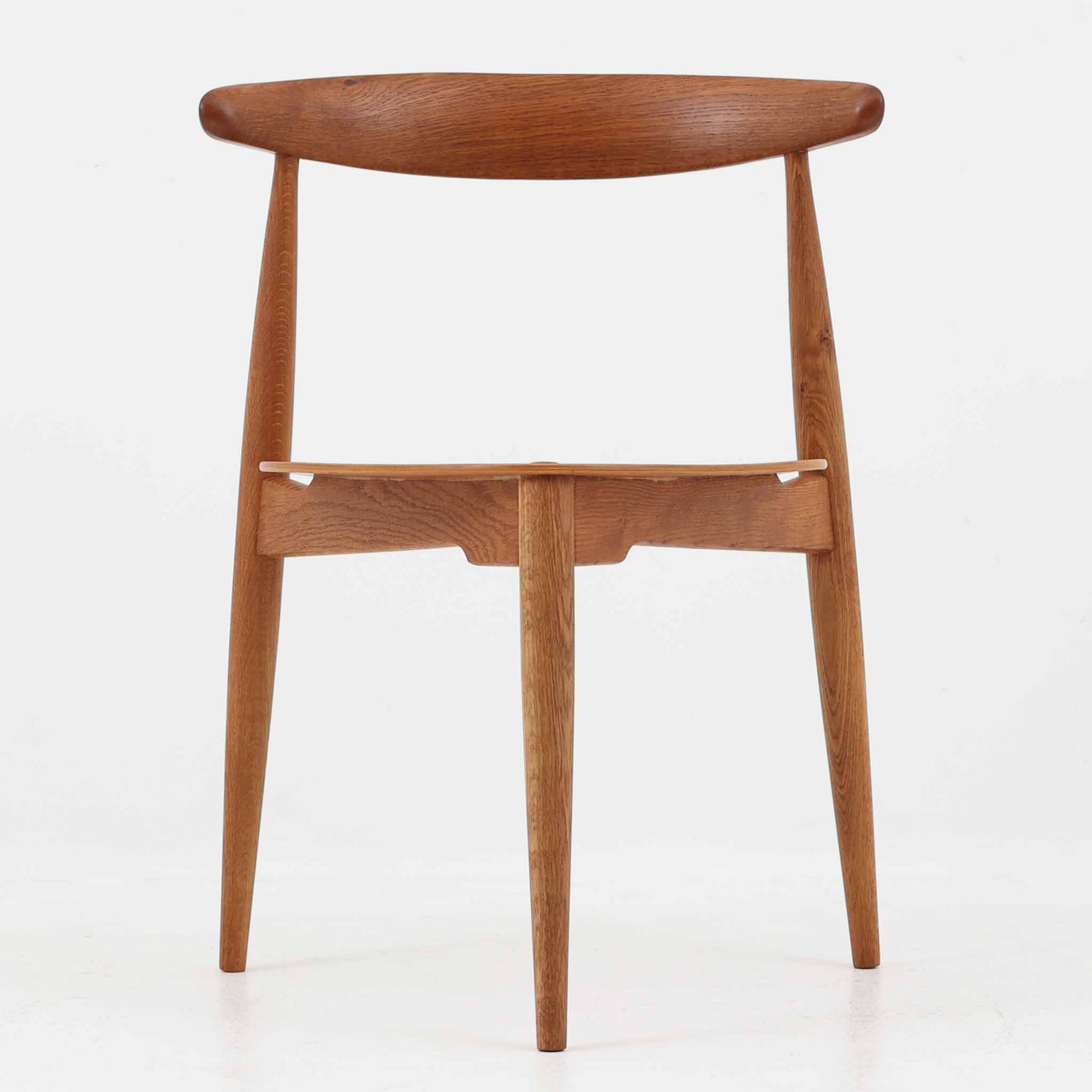 Hans J. Wegnerがデザインし、Fritz Hansen社より発表されたFH4103チェアは、三角形に近い座面と滑らかな曲線を描く笠木が特徴の北欧ビンテージ家具です。フレームには堅牢なオーク材、座面には温かみあるチーク材を組み合わせ、素材のコントラストが美しいバランスを生み出しています。彫刻的なフォルムながら軽やかで実用的な構造は、ダイニングチェアとしてはもちろん、空間のアクセントピースとしても存在感を放ちます。経年による木肌の深い風合いが、ビンテージならではの魅力を引き立てています。