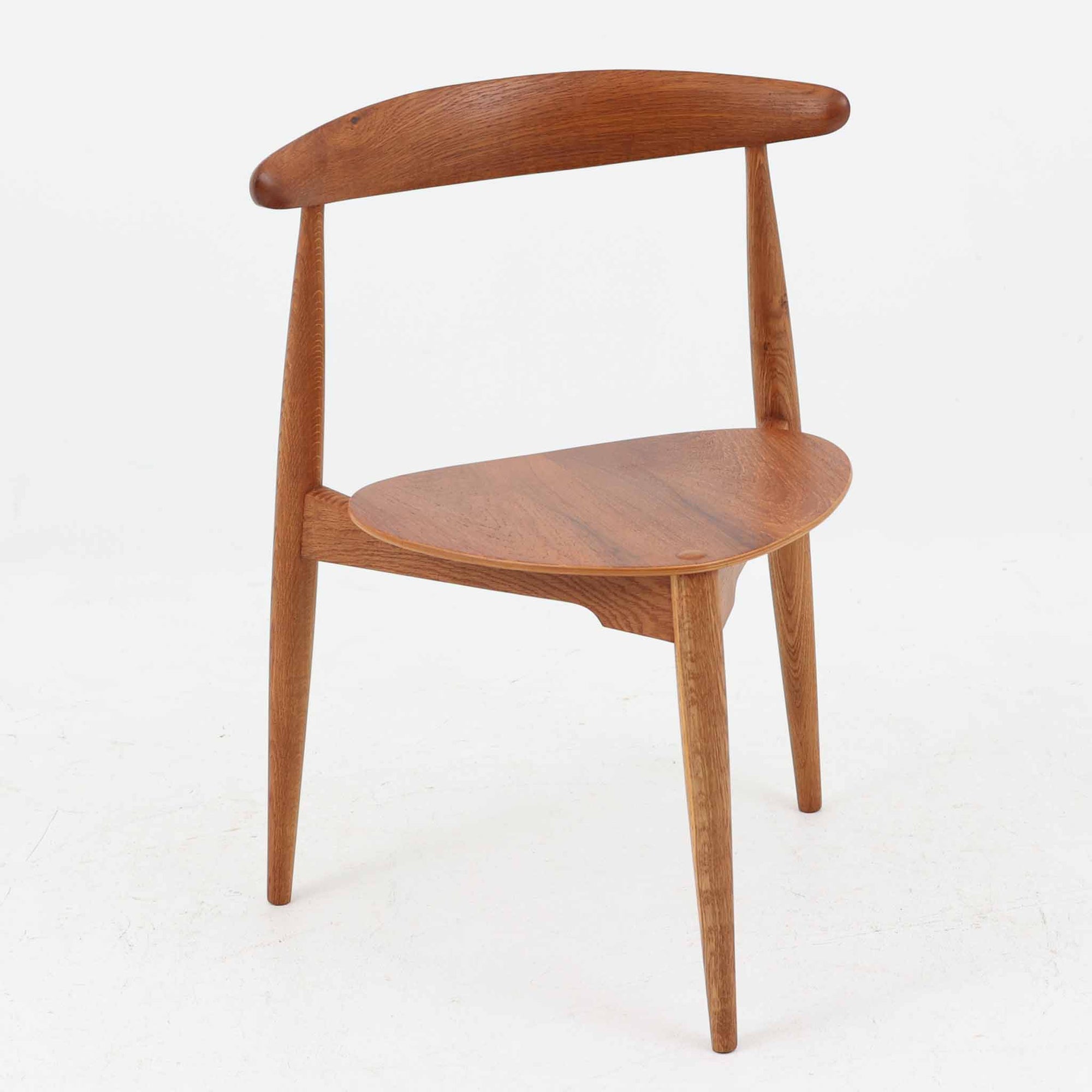 Hans J. Wegnerがデザインし、Fritz Hansen社より発表されたFH4103チェアは、三角形に近い座面と滑らかな曲線を描く笠木が特徴の北欧ビンテージ家具です。フレームには堅牢なオーク材、座面には温かみあるチーク材を組み合わせ、素材のコントラストが美しいバランスを生み出しています。彫刻的なフォルムながら軽やかで実用的な構造は、ダイニングチェアとしてはもちろん、空間のアクセントピースとしても存在感を放ちます。経年による木肌の深い風合いが、ビンテージならではの魅力を引き立てています。