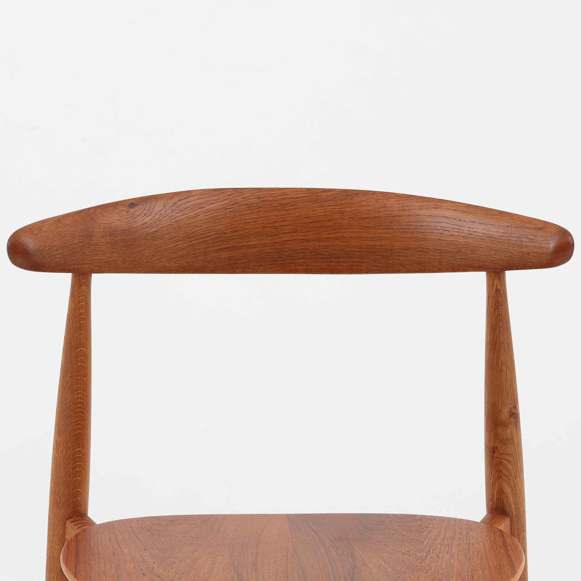 Hans J. Wegnerがデザインし、Fritz Hansen社より発表されたFH4103チェアは、三角形に近い座面と滑らかな曲線を描く笠木が特徴の北欧ビンテージ家具です。フレームには堅牢なオーク材、座面には温かみあるチーク材を組み合わせ、素材のコントラストが美しいバランスを生み出しています。彫刻的なフォルムながら軽やかで実用的な構造は、ダイニングチェアとしてはもちろん、空間のアクセントピースとしても存在感を放ちます。経年による木肌の深い風合いが、ビンテージならではの魅力を引き立てています。
