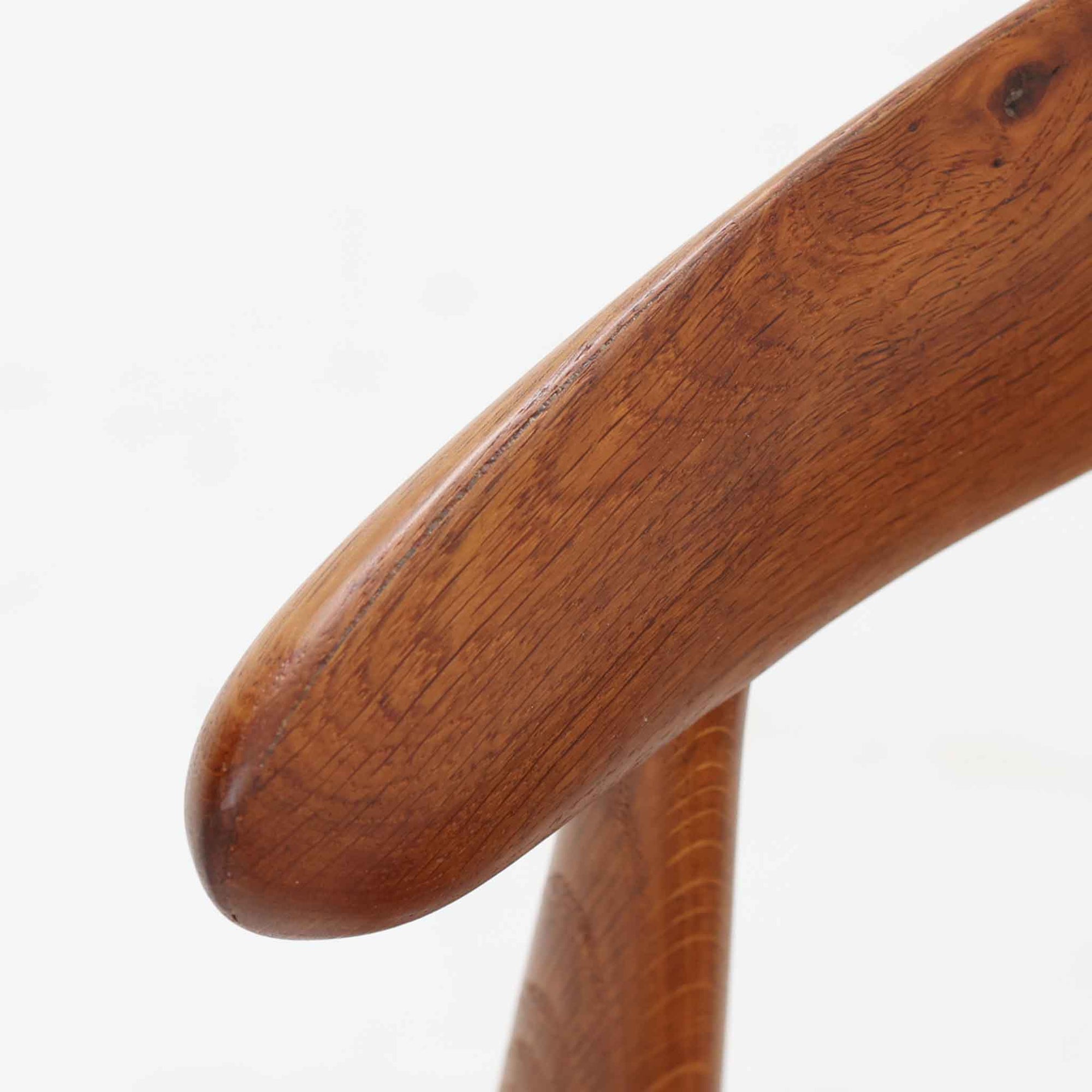 Hans J. Wegnerがデザインし、Fritz Hansen社より発表されたFH4103チェアは、三角形に近い座面と滑らかな曲線を描く笠木が特徴の北欧ビンテージ家具です。フレームには堅牢なオーク材、座面には温かみあるチーク材を組み合わせ、素材のコントラストが美しいバランスを生み出しています。彫刻的なフォルムながら軽やかで実用的な構造は、ダイニングチェアとしてはもちろん、空間のアクセントピースとしても存在感を放ちます。経年による木肌の深い風合いが、ビンテージならではの魅力を引き立てています。