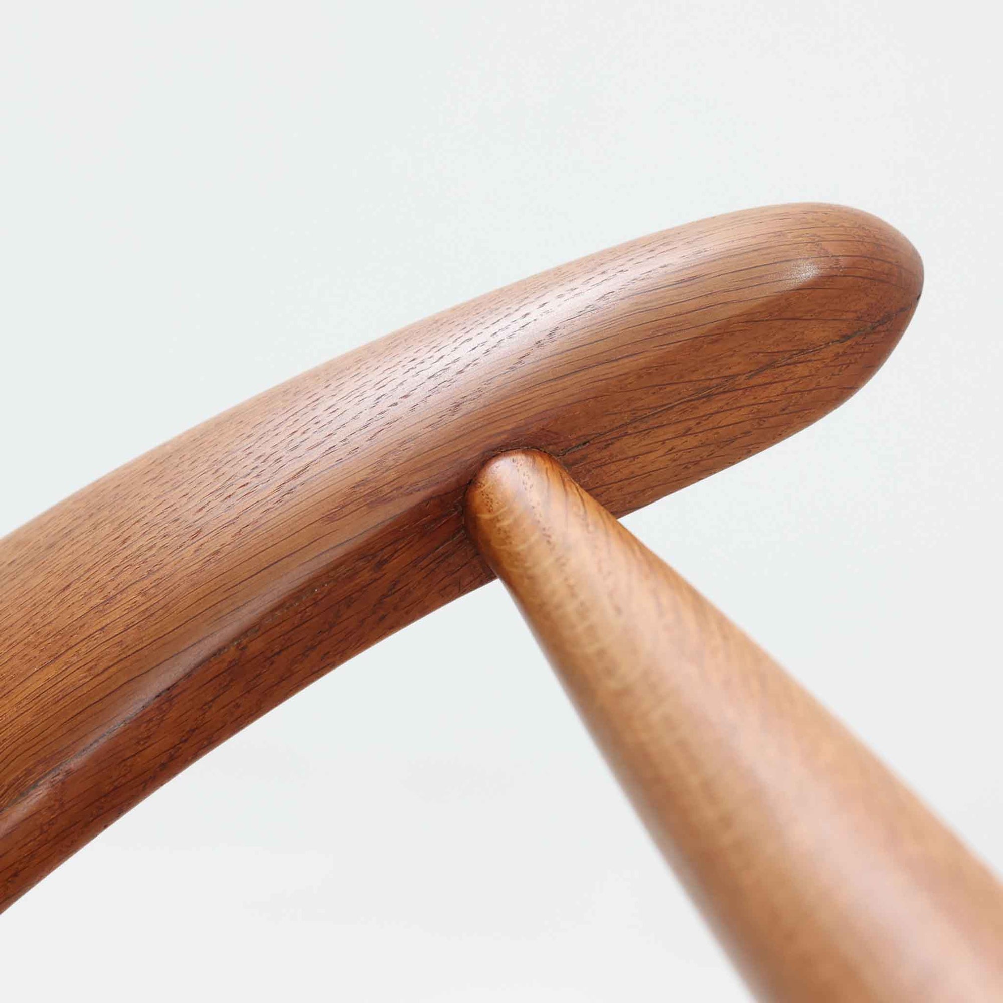 Hans J. Wegnerがデザインし、Fritz Hansen社より発表されたFH4103チェアは、三角形に近い座面と滑らかな曲線を描く笠木が特徴の北欧ビンテージ家具です。フレームには堅牢なオーク材、座面には温かみあるチーク材を組み合わせ、素材のコントラストが美しいバランスを生み出しています。彫刻的なフォルムながら軽やかで実用的な構造は、ダイニングチェアとしてはもちろん、空間のアクセントピースとしても存在感を放ちます。経年による木肌の深い風合いが、ビンテージならではの魅力を引き立てています。