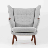 Hans J. Wegnerによってデザインされ、AP Stolen社より製造された名作AP-19、通称「ベアチェア」は、その名の通り熊が抱きかかえるような形状のアームが特徴のシングルソファです。張りぐるみのシートを支えるチーク材の脚部は、繊細さと力強さを兼ね備えた見事な造形で、ウェグナーらしい有機的なフォルムと高い快適性が融合した一台です。張地にはグレー系のファブリックを使用し、空間に馴染みやすい落ち着いた印象に仕上げられています。名作ゆえに現存数も限られ、ビンテージ市場でも高い評価を受ける希少な逸品です。