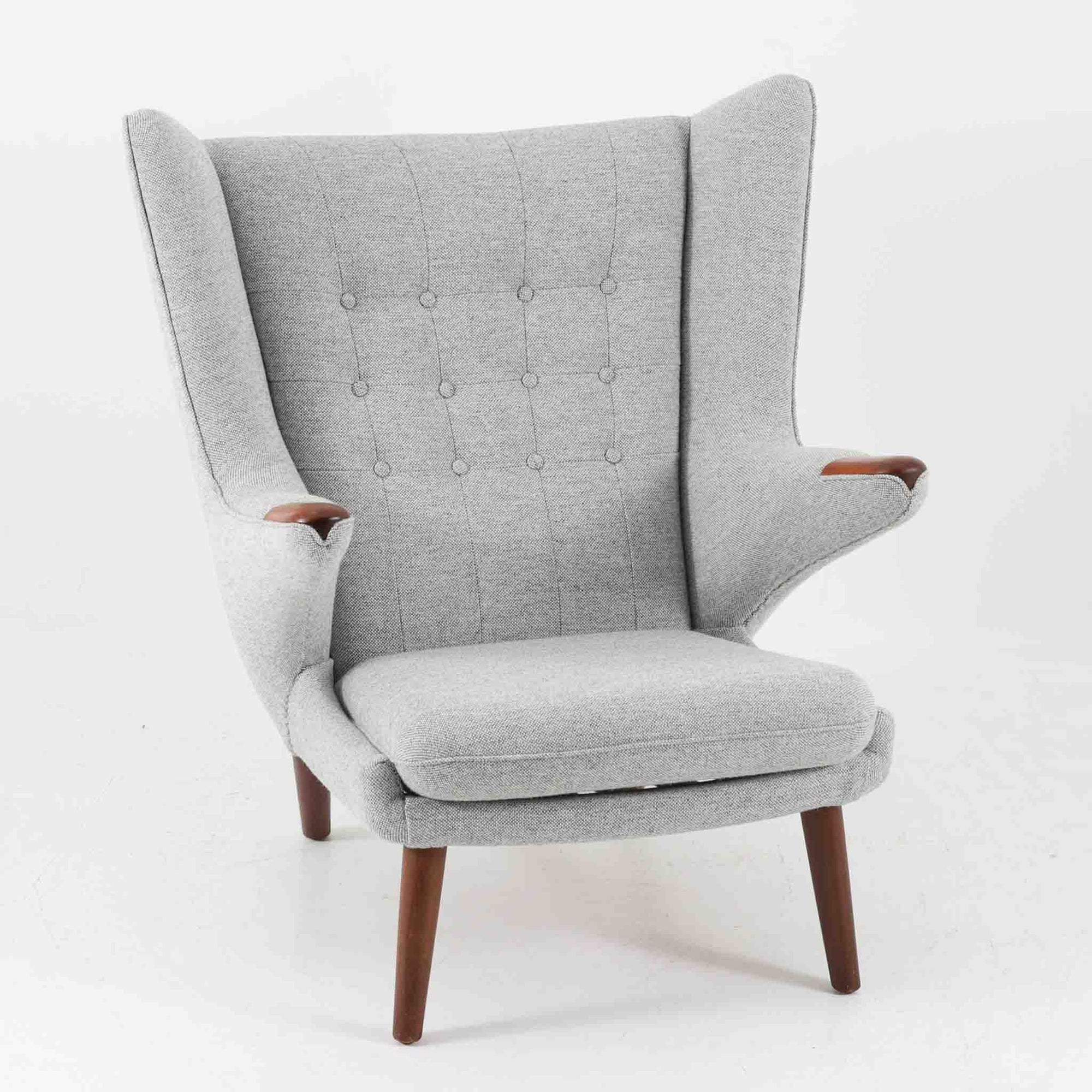 Hans J. Wegnerによってデザインされ、AP Stolen社より製造された名作AP-19、通称「ベアチェア」は、その名の通り熊が抱きかかえるような形状のアームが特徴のシングルソファです。張りぐるみのシートを支えるチーク材の脚部は、繊細さと力強さを兼ね備えた見事な造形で、ウェグナーらしい有機的なフォルムと高い快適性が融合した一台です。張地にはグレー系のファブリックを使用し、空間に馴染みやすい落ち着いた印象に仕上げられています。名作ゆえに現存数も限られ、ビンテージ市場でも高い評価を受ける希少な逸品です。