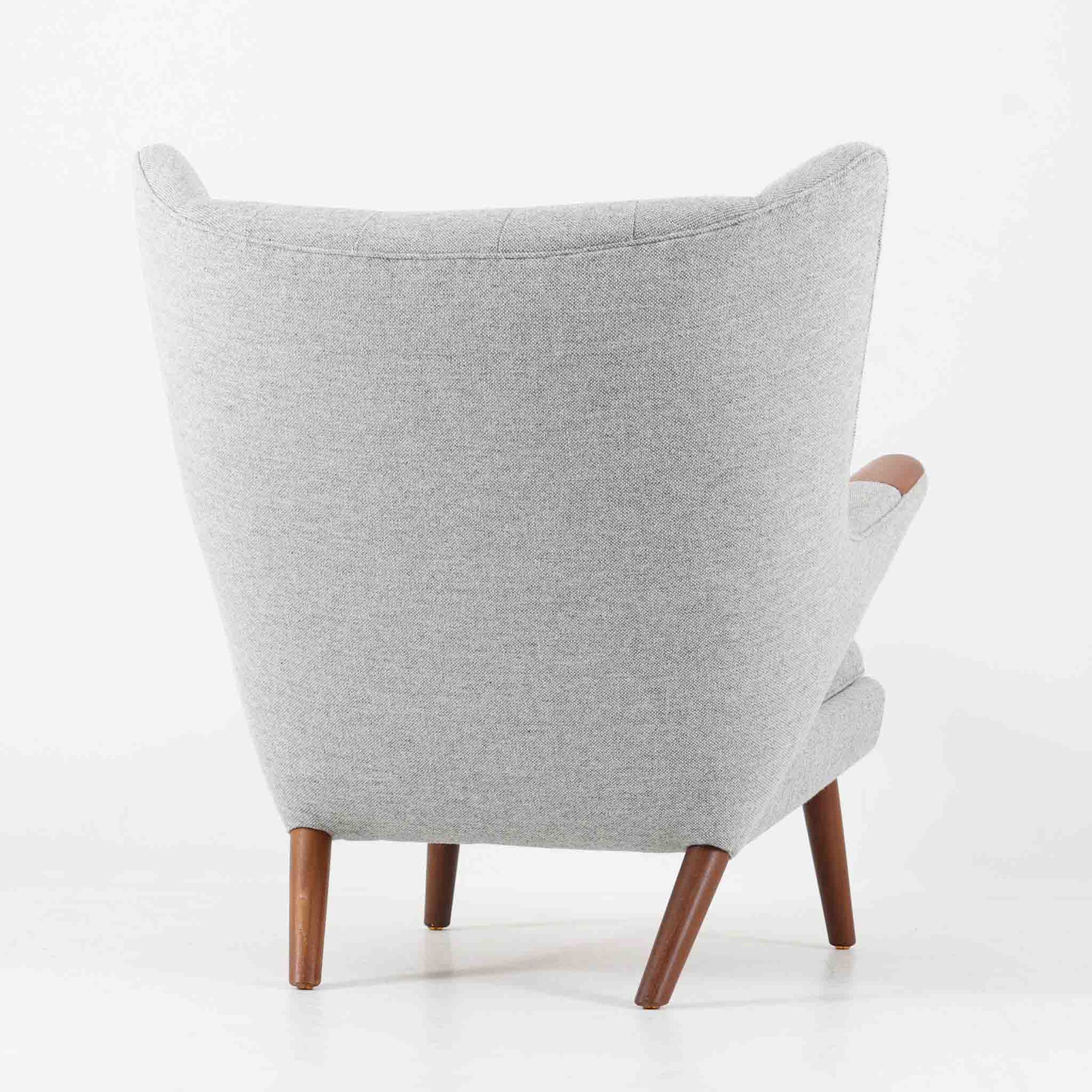 Hans J. Wegnerによってデザインされ、AP Stolen社より製造された名作AP-19、通称「ベアチェア」は、その名の通り熊が抱きかかえるような形状のアームが特徴のシングルソファです。張りぐるみのシートを支えるチーク材の脚部は、繊細さと力強さを兼ね備えた見事な造形で、ウェグナーらしい有機的なフォルムと高い快適性が融合した一台です。張地にはグレー系のファブリックを使用し、空間に馴染みやすい落ち着いた印象に仕上げられています。名作ゆえに現存数も限られ、ビンテージ市場でも高い評価を受ける希少な逸品です。