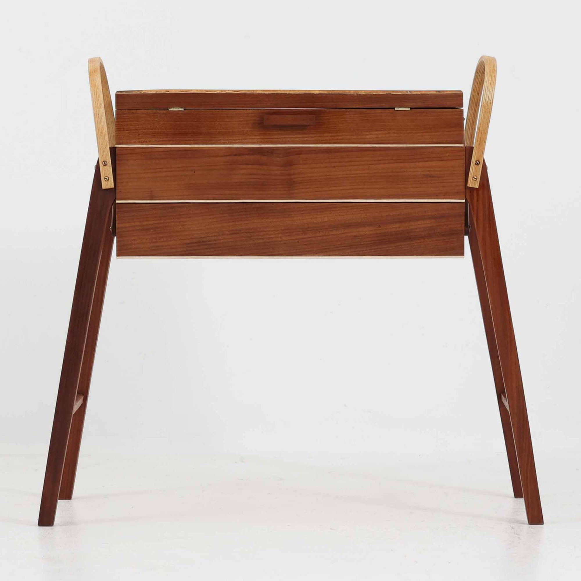 こちらのソーイングボックスは、チーク材とビーチ材を組み合わせた軽やかな構成が魅力の北欧ビンテージ品で、トップのフラップを開くと段違いに展開するトレイと下段の引き出しが現れる優れた収納構造を備え、裁縫道具や小物を効率よく整理できます。柔らかく曲げられた左右のビーチ材の持ち手がアクセントとなり、職人技の感じられる繊細な作りと経年で深まった木肌の風合いが空間に温かな存在感をもたらします。リビングやワークスペースのサイドテーブルとしても実用的にお使いいただけます。