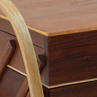 こちらのソーイングボックスは、チーク材とビーチ材を組み合わせた軽やかな構成が魅力の北欧ビンテージ品で、トップのフラップを開くと段違いに展開するトレイと下段の引き出しが現れる優れた収納構造を備え、裁縫道具や小物を効率よく整理できます。柔らかく曲げられた左右のビーチ材の持ち手がアクセントとなり、職人技の感じられる繊細な作りと経年で深まった木肌の風合いが空間に温かな存在感をもたらします。リビングやワークスペースのサイドテーブルとしても実用的にお使いいただけます。