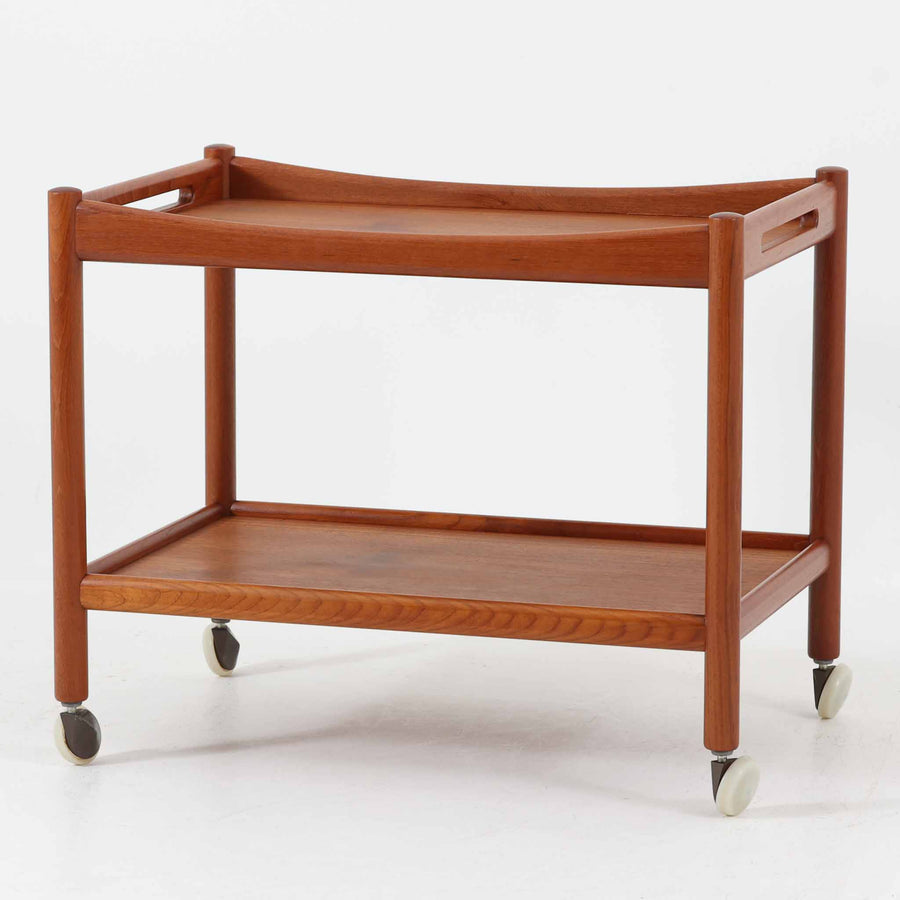 Hans J. Wegnerがデザインし、Andreas Tuck社より製造されたキャスターワゴン「AT45」は、チーク材の豊かな表情と機能美が融合した北欧ビンテージの逸品です。両サイドには持ち運びに便利な取っ手が付き、脚先にはスムーズに動くキャスターを備えているため、サービングや配膳台として活躍します。緩やかな曲線を描くフレームと丁寧な仕上げに、ウェグナーらしい美意識が宿る一台です。