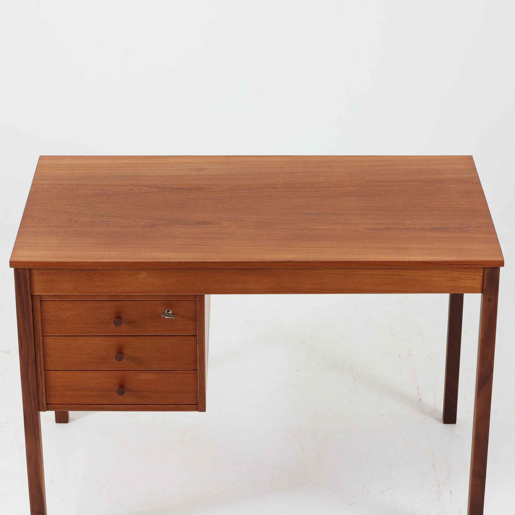デンマーク製の片袖デスクは、北欧ビンテージ家具らしい端正な佇まいが魅力です。チーク材を用いた温かみのある色合いと、美しい木目が空間に上質な雰囲気を添えます。幅104cmとコンパクトなサイズ感でありながら、左側に3杯の引き出しを備え、上段は鍵付きで大切な書類や小物を安心して収納可能。シンプルながら堅牢な造りと細部まで行き届いた職人技が感じられ、長年の使用にも耐えうる実用性を兼ね備えています。ワークデスクや書斎机としてはもちろん、リビングや寝室に置いても自然に馴染み、北欧家具ならではの温もりと機能美を楽しめる一台です。