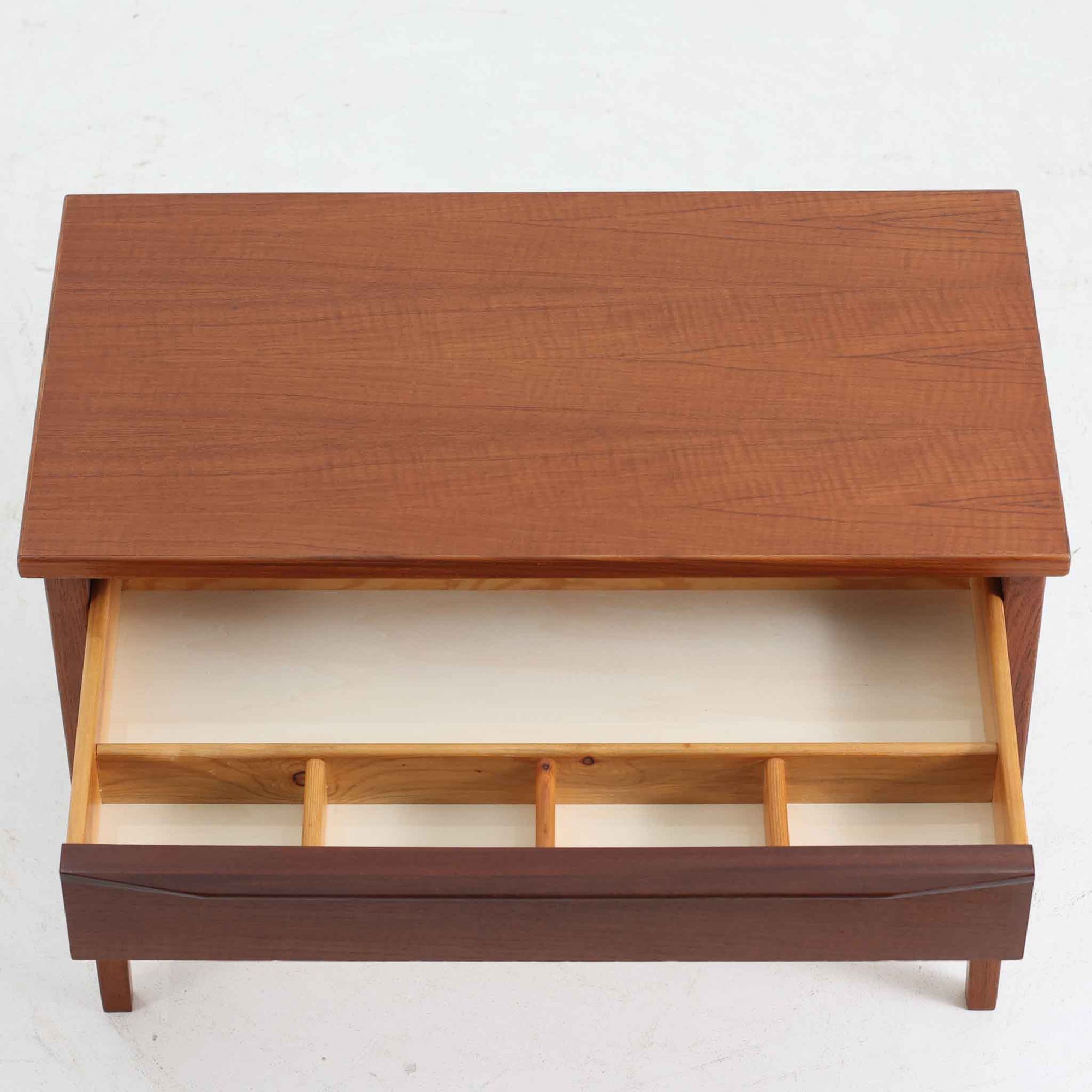 デンマーク製2段チェストです。無駄のないシンプルなフォルムとチーク材特有の深みのある色合いが美しく、北欧らしい上品な佇まいを感じさせます。引き出しの前板にはデンマーク家具らしい取手が施され、素材の質感を引き立てるデザインです。上段には仕切りが設けられており、小物の整理にも便利です。コンパクトなサイズながら収納力があり、リビングやベッドサイドなど幅広いシーンで活躍します。経年により艶を増した木肌が空間に温もりを添える一品です。