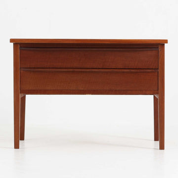 デンマーク製2段チェストです。無駄のないシンプルなフォルムとチーク材特有の深みのある色合いが美しく、北欧らしい上品な佇まいを感じさせます。引き出しの前板にはデンマーク家具らしい取手が施され、素材の質感を引き立てるデザインです。上段には仕切りが設けられており、小物の整理にも便利です。コンパクトなサイズながら収納力があり、リビングやベッドサイドなど幅広いシーンで活躍します。経年により艶を増した木肌が空間に温もりを添える一品です。