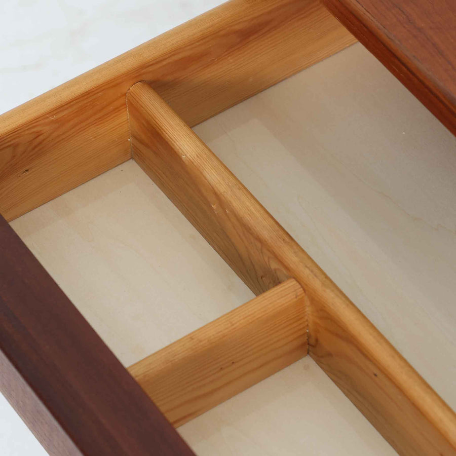 デンマーク製2段チェストです。無駄のないシンプルなフォルムとチーク材特有の深みのある色合いが美しく、北欧らしい上品な佇まいを感じさせます。引き出しの前板にはデンマーク家具らしい取手が施され、素材の質感を引き立てるデザインです。上段には仕切りが設けられており、小物の整理にも便利です。コンパクトなサイズながら収納力があり、リビングやベッドサイドなど幅広いシーンで活躍します。経年により艶を増した木肌が空間に温もりを添える一品です。