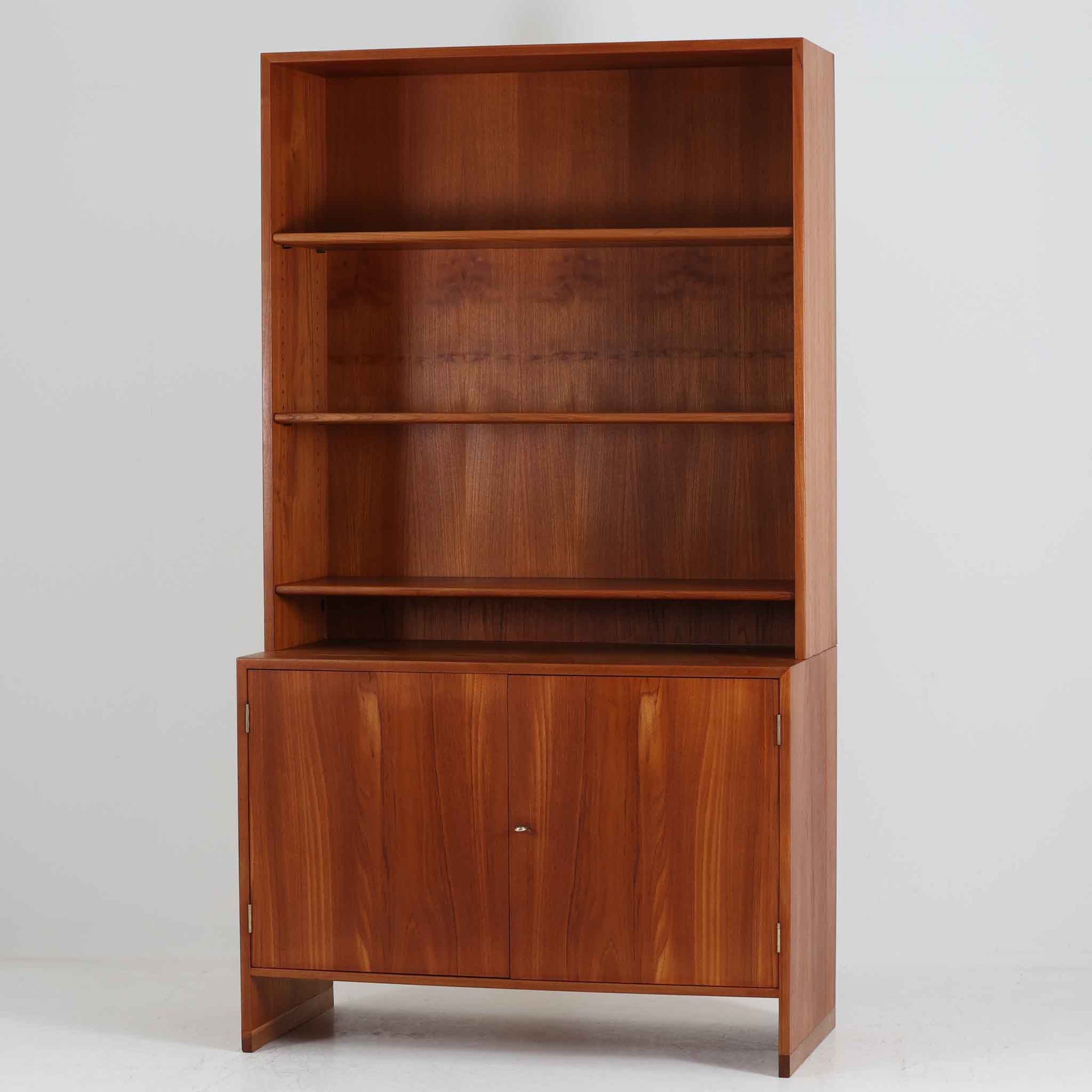 デンマークの巨匠Hans J. Wegner（ハンス・J・ウェグナー）がRY Mobler社のためにデザインしたディスプレイシェルフ「RY5 / RY15」です。上質なチーク材とオーク材を組み合わせ、下段収納部の取手には真鍮を用いた精緻なつくりが特徴です。シンプルながらも素材の美しさが際立ち、ウェグナーらしい温かみのあるデザインに仕上がっています。上段の棚は高さ調整が可能で、下段には仕切り付きの収納スペースを備え、実用性にも優れます。経年により深みを増した木肌の風合いが美しく、リビングや書斎で本や器を飾るなど、多用途に活躍する北欧ビンテージ家具です。