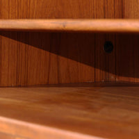 デンマークの巨匠Hans J. Wegner（ハンス・J・ウェグナー）がRY Mobler社のためにデザインしたディスプレイシェルフ「RY5 / RY15」です。上質なチーク材とオーク材を組み合わせ、下段収納部の取手には真鍮を用いた精緻なつくりが特徴です。シンプルながらも素材の美しさが際立ち、ウェグナーらしい温かみのあるデザインに仕上がっています。上段の棚は高さ調整が可能で、下段には仕切り付きの収納スペースを備え、実用性にも優れます。経年により深みを増した木肌の風合いが美しく、リビングや書斎で本や器を飾るなど、多用途に活躍する北欧ビンテージ家具です。