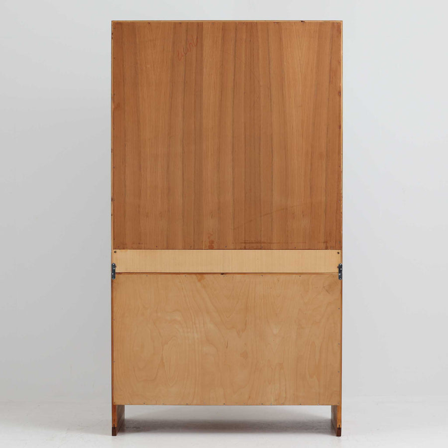 デンマークの巨匠Hans J. Wegner（ハンス・J・ウェグナー）がRY Mobler社のためにデザインしたディスプレイシェルフ「RY5 / RY15」です。上質なチーク材とオーク材を組み合わせ、下段収納部の取手には真鍮を用いた精緻なつくりが特徴です。シンプルながらも素材の美しさが際立ち、ウェグナーらしい温かみのあるデザインに仕上がっています。上段の棚は高さ調整が可能で、下段には仕切り付きの収納スペースを備え、実用性にも優れます。経年により深みを増した木肌の風合いが美しく、リビングや書斎で本や器を飾るなど、多用途に活躍する北欧ビンテージ家具です。