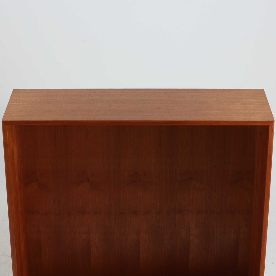 デンマークの巨匠Hans J. Wegner（ハンス・J・ウェグナー）がRY Mobler社のためにデザインしたディスプレイシェルフ「RY5 / RY15」です。上質なチーク材とオーク材を組み合わせ、下段収納部の取手には真鍮を用いた精緻なつくりが特徴です。シンプルながらも素材の美しさが際立ち、ウェグナーらしい温かみのあるデザインに仕上がっています。上段の棚は高さ調整が可能で、下段には仕切り付きの収納スペースを備え、実用性にも優れます。経年により深みを増した木肌の風合いが美しく、リビングや書斎で本や器を飾るなど、多用途に活躍する北欧ビンテージ家具です。