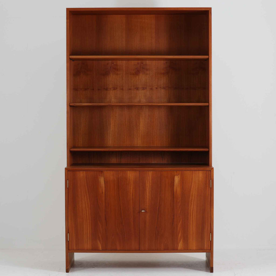 デンマークの巨匠Hans J. Wegner（ハンス・J・ウェグナー）がRY Mobler社のためにデザインしたディスプレイシェルフ「RY5 / RY15」です。上質なチーク材とオーク材を組み合わせ、下段収納部の取手には真鍮を用いた精緻なつくりが特徴です。シンプルながらも素材の美しさが際立ち、ウェグナーらしい温かみのあるデザインに仕上がっています。上段の棚は高さ調整が可能で、下段には仕切り付きの収納スペースを備え、実用性にも優れます。経年により深みを増した木肌の風合いが美しく、リビングや書斎で本や器を飾るなど、多用途に活躍する北欧ビンテージ家具です。