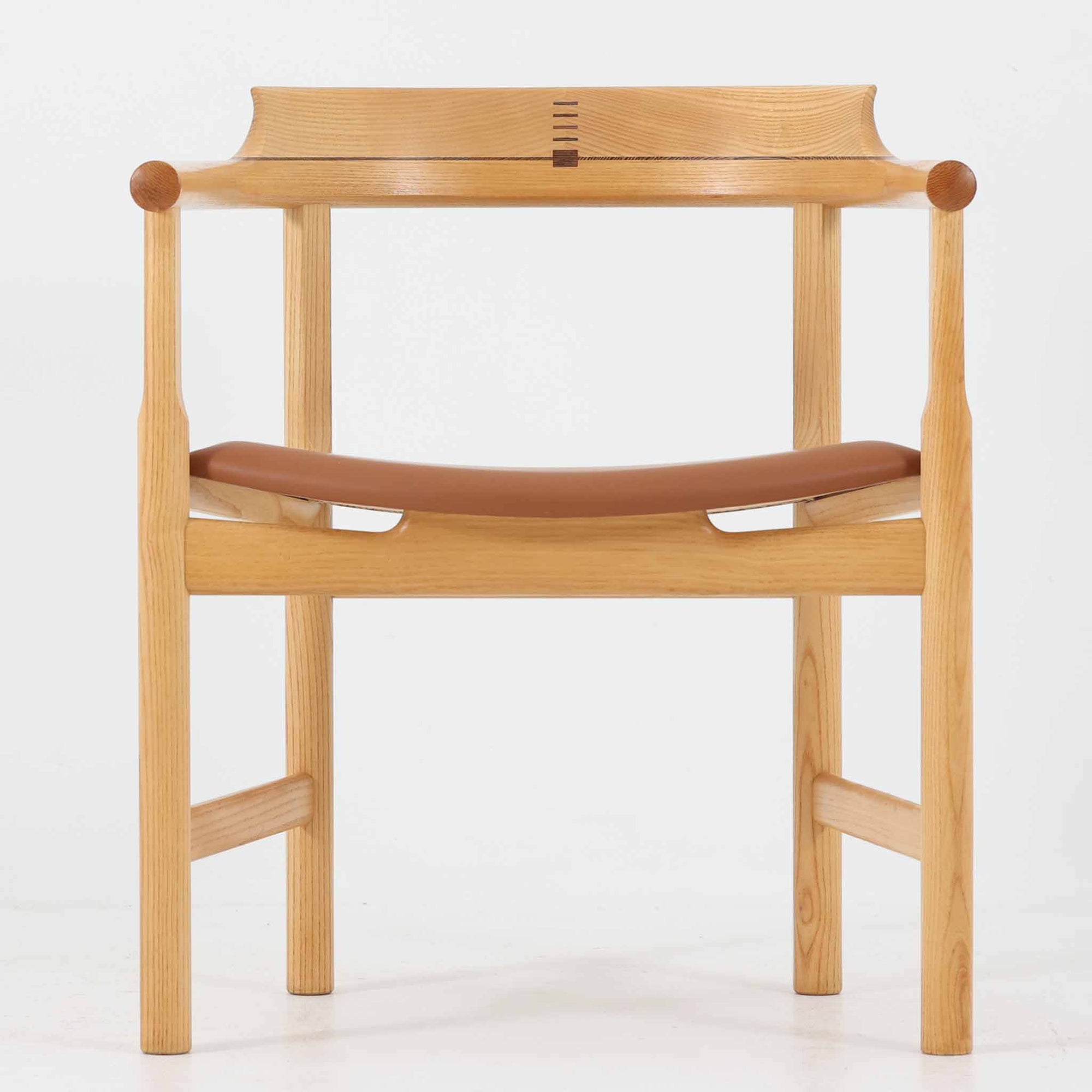 Hans J. Wegnerが1975年にデザインし、PP Mobler社が製造したPP52 Captain's Chairは、背からアームまで滑らかにつながる一体成型の美しいフォルムが魅力のアームチェアです。素材には木目の美しいアッシュ材と本革が用いられ、背面には象徴的な埋木の意匠が施されています。座面はゆったりとしたカーブで快適な座り心地を実現し、ダイニングからデスクシーンまで幅広く対応します。現在も製造されており、現行品の販売価格は約90～100万円程度となっています。