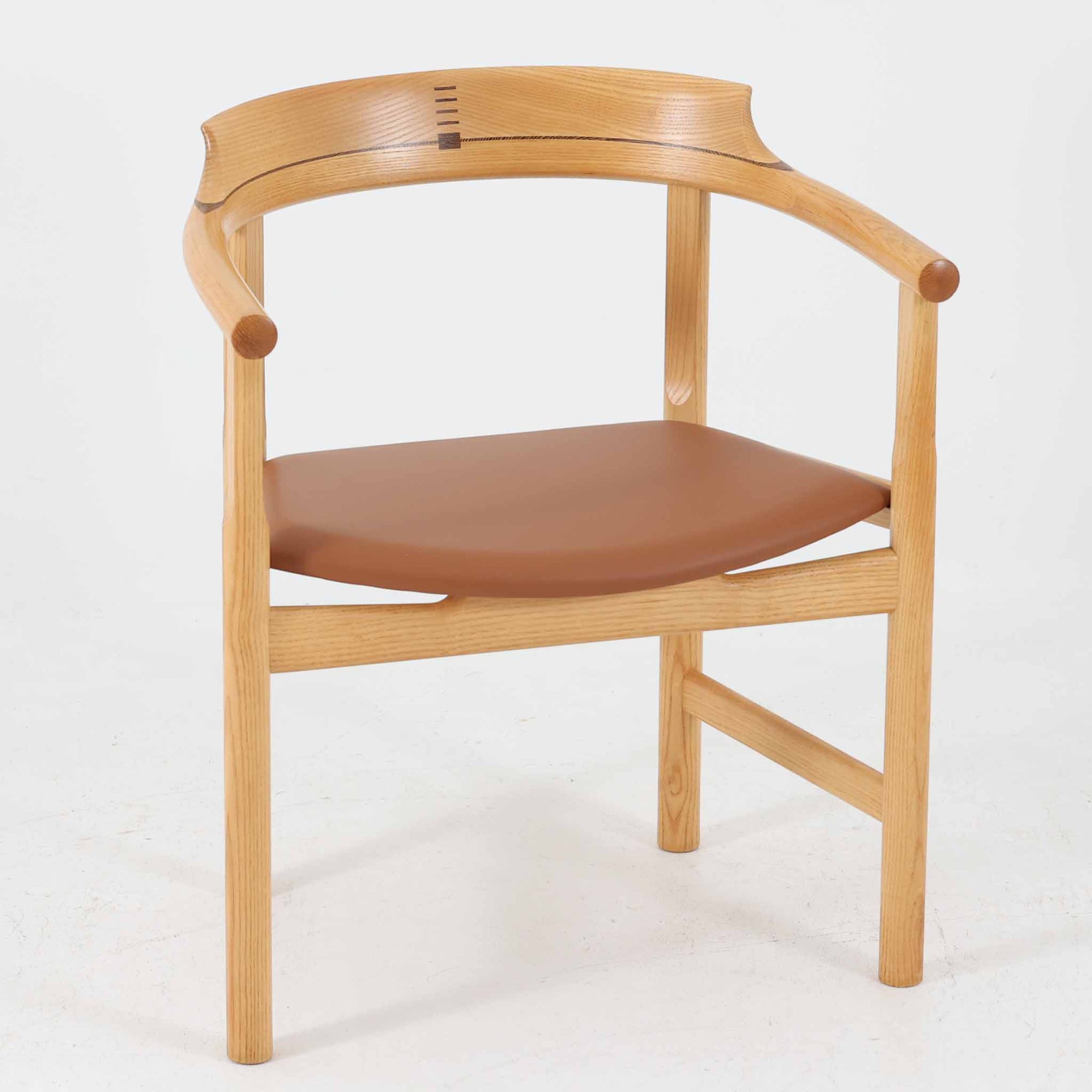 Hans J. Wegnerが1975年にデザインし、PP Mobler社が製造したPP52 Captain's Chairは、背からアームまで滑らかにつながる一体成型の美しいフォルムが魅力のアームチェアです。素材には木目の美しいアッシュ材と本革が用いられ、背面には象徴的な埋木の意匠が施されています。座面はゆったりとしたカーブで快適な座り心地を実現し、ダイニングからデスクシーンまで幅広く対応します。現在も製造されており、現行品の販売価格は約90～100万円程度となっています。