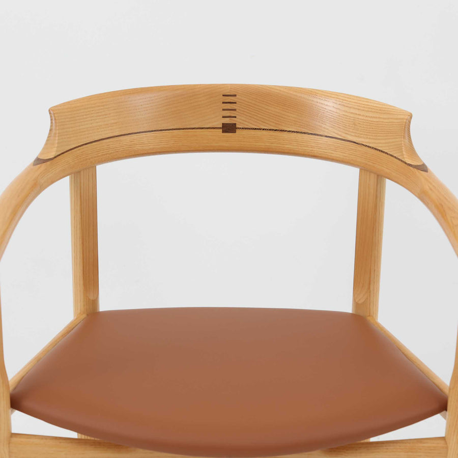 Hans J. Wegnerが1975年にデザインし、PP Mobler社が製造したPP52 Captain's Chairは、背からアームまで滑らかにつながる一体成型の美しいフォルムが魅力のアームチェアです。素材には木目の美しいアッシュ材と本革が用いられ、背面には象徴的な埋木の意匠が施されています。座面はゆったりとしたカーブで快適な座り心地を実現し、ダイニングからデスクシーンまで幅広く対応します。現在も製造されており、現行品の販売価格は約90～100万円程度となっています。