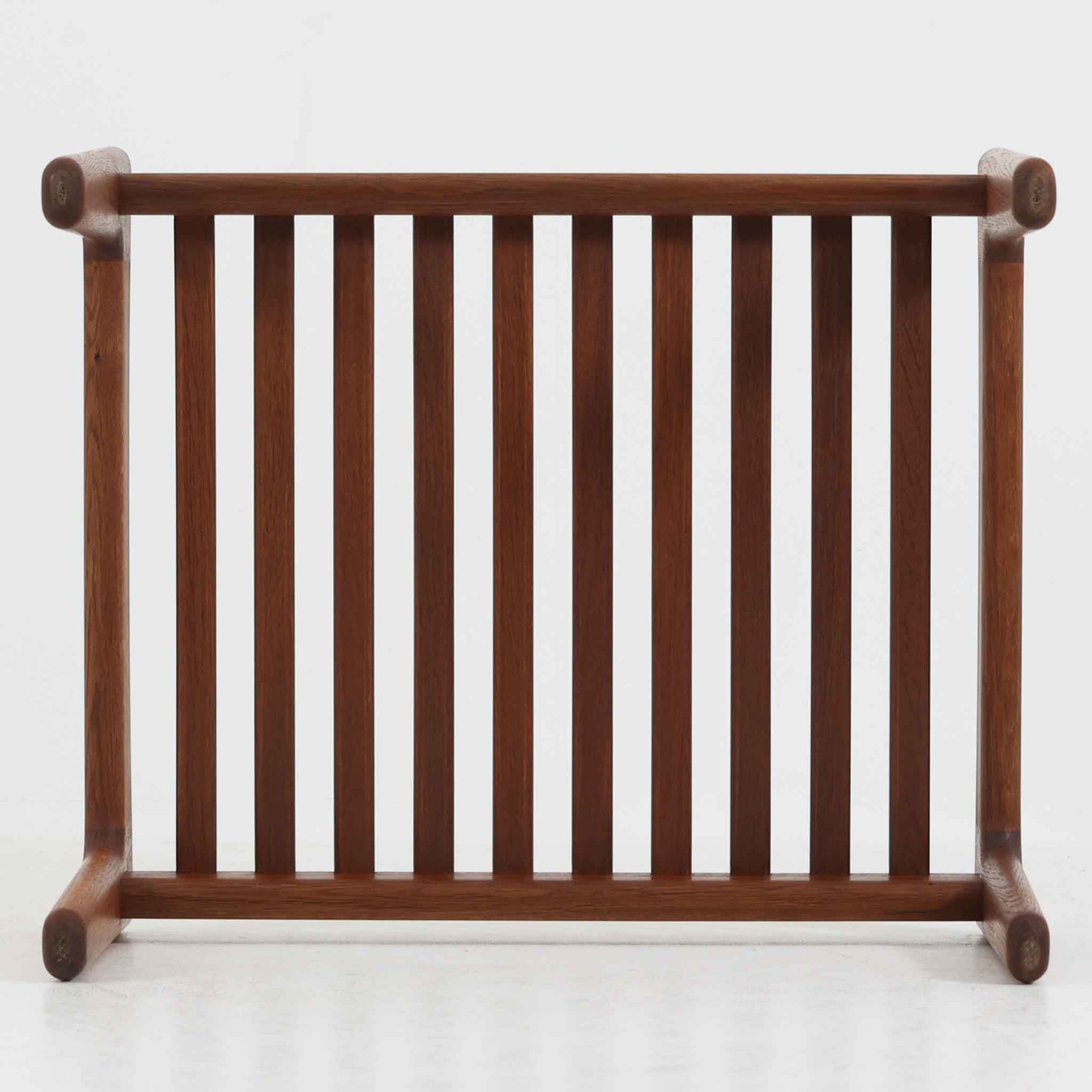 ハンス・J・ウェグナーがデザインし、ゲタマ社から発表されたGE290オットマンは、堅牢なオーク材のフレームと、ウール混紡のざっくりとした風合いを持つダークグレーの張地が美しく調和した北欧ビンテージ家具です。直線的でありながら丸みを帯びた脚部が軽快な印象を与え、ソファと組み合わせてフットレストとして、あるいは単体で腰掛けとしてもお使いいただけます。オーク材の色味は少し濃いめで、本革カバー仕様のビンテージモデルのためクッション内部にスプリングは元々内包されないタイプです。経年によって深まった木肌の風合いと上質な張地が、空間に落ち着いた存在感をもたらす逸品です。