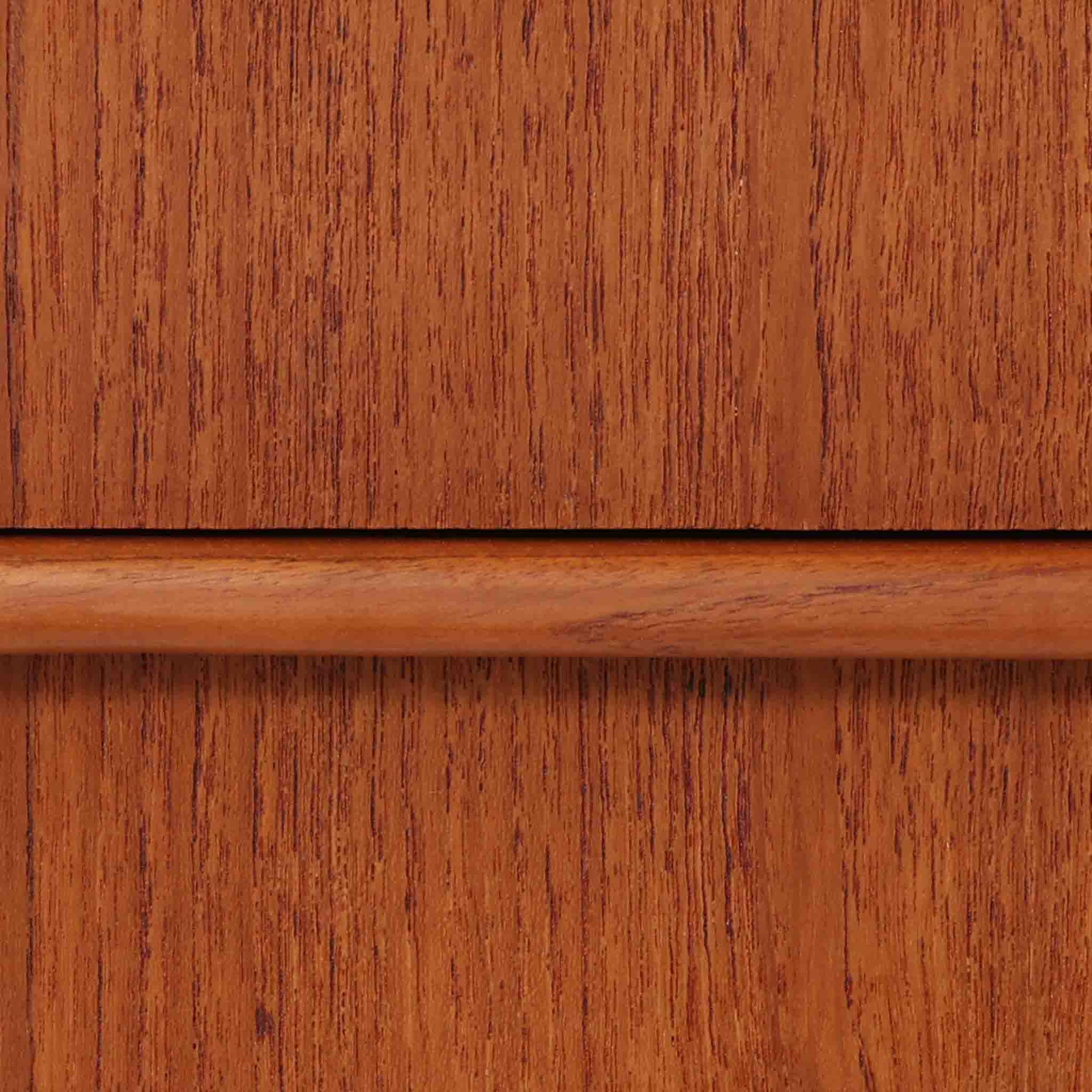 チーク材を使用したデンマーク製の3段チェストで、直線的な本体に対して丸みを帯びた引き手と細身のテーパードレッグが柔らかな印象を与え、さらに天板左右に伸びた耳のような張り出しがデザインのアクセントとなり、北欧らしい優雅な佇まいが感じられます。引き出しは3杯備え、衣類や小物収納に適したサイズ感で、ベッドサイドやリビングの一角に置きやすく、花器や照明のディスプレイ台としても楽しめます。シンプルな造形ながら木目の美しさが際立ち、空間に温かみと落ち着きを添えてくれるビンテージ家具です。