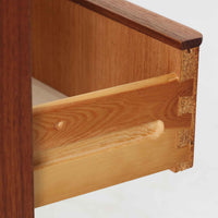 チーク材を使用したデンマーク製の3段チェストで、直線的な本体に対して丸みを帯びた引き手と細身のテーパードレッグが柔らかな印象を与え、さらに天板左右に伸びた耳のような張り出しがデザインのアクセントとなり、北欧らしい優雅な佇まいが感じられます。引き出しは3杯備え、衣類や小物収納に適したサイズ感で、ベッドサイドやリビングの一角に置きやすく、花器や照明のディスプレイ台としても楽しめます。シンプルな造形ながら木目の美しさが際立ち、空間に温かみと落ち着きを添えてくれるビンテージ家具です。