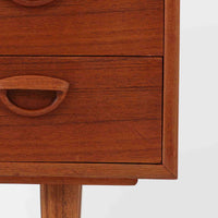 カイ・クリスチャンセンが手掛け、フェルドバレス・モーベルファブリック社によって製作された4段チェストは、北欧ビンテージらしい端正な佇まいと高い実用性を兼ね備えた一台です。良質なチーク材を用いた本体は、木目の美しさが前面に表れ、半円状に削り出された取手や細身のテーパードレッグが、全体に軽やかで洗練された印象を与えています。引き出しは深さにゆとりがあり収納力も十分で、衣類や小物の整理に最適です。経年変化によって深みを増したチークの色合いが空間に温もりを添え、リビングや寝室、書斎など幅広いシーンで主役として活躍します。