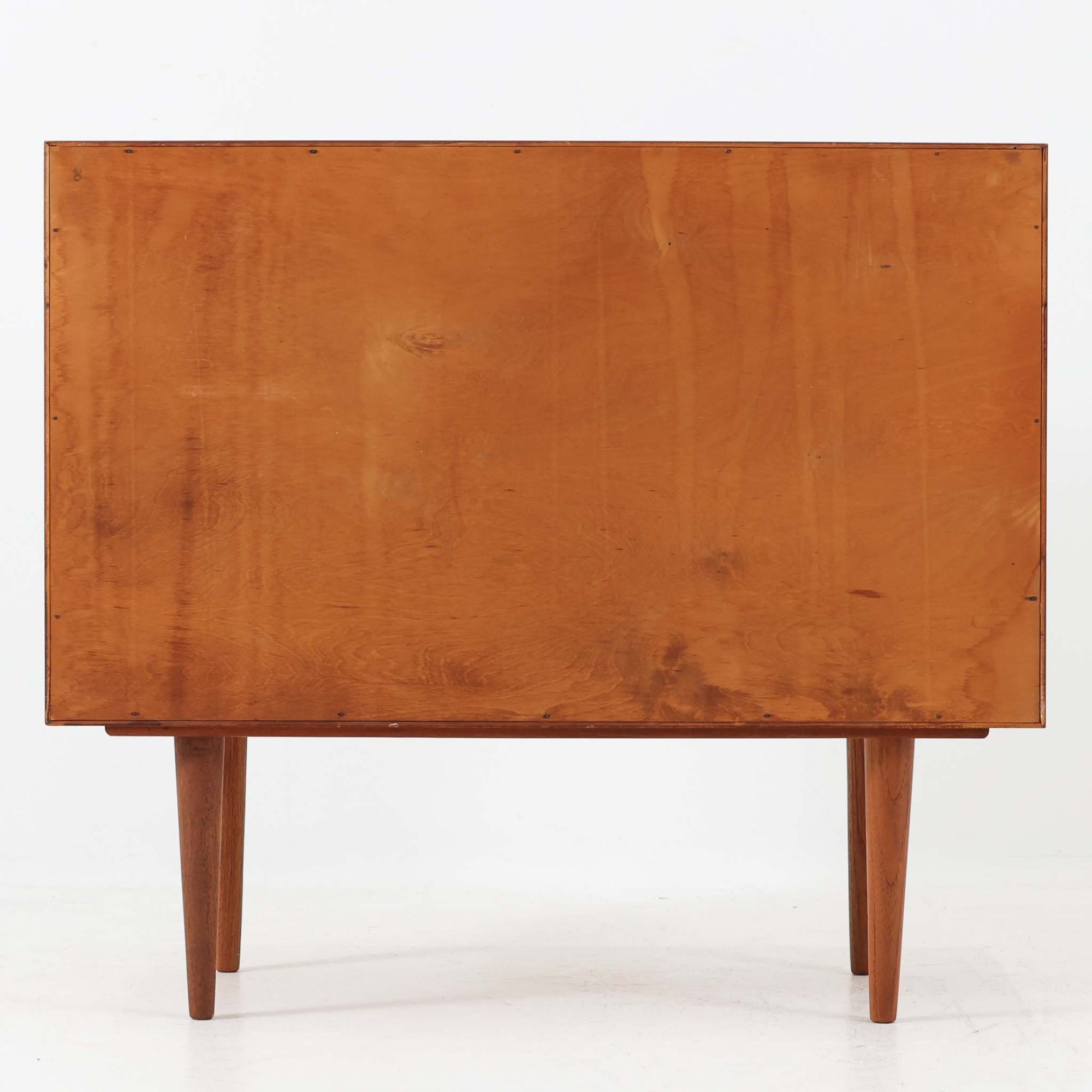 カイ・クリスチャンセンが手掛け、フェルドバレス・モーベルファブリック社によって製作された4段チェストは、北欧ビンテージらしい端正な佇まいと高い実用性を兼ね備えた一台です。良質なチーク材を用いた本体は、木目の美しさが前面に表れ、半円状に削り出された取手や細身のテーパードレッグが、全体に軽やかで洗練された印象を与えています。引き出しは深さにゆとりがあり収納力も十分で、衣類や小物の整理に最適です。経年変化によって深みを増したチークの色合いが空間に温もりを添え、リビングや寝室、書斎など幅広いシーンで主役として活躍します。