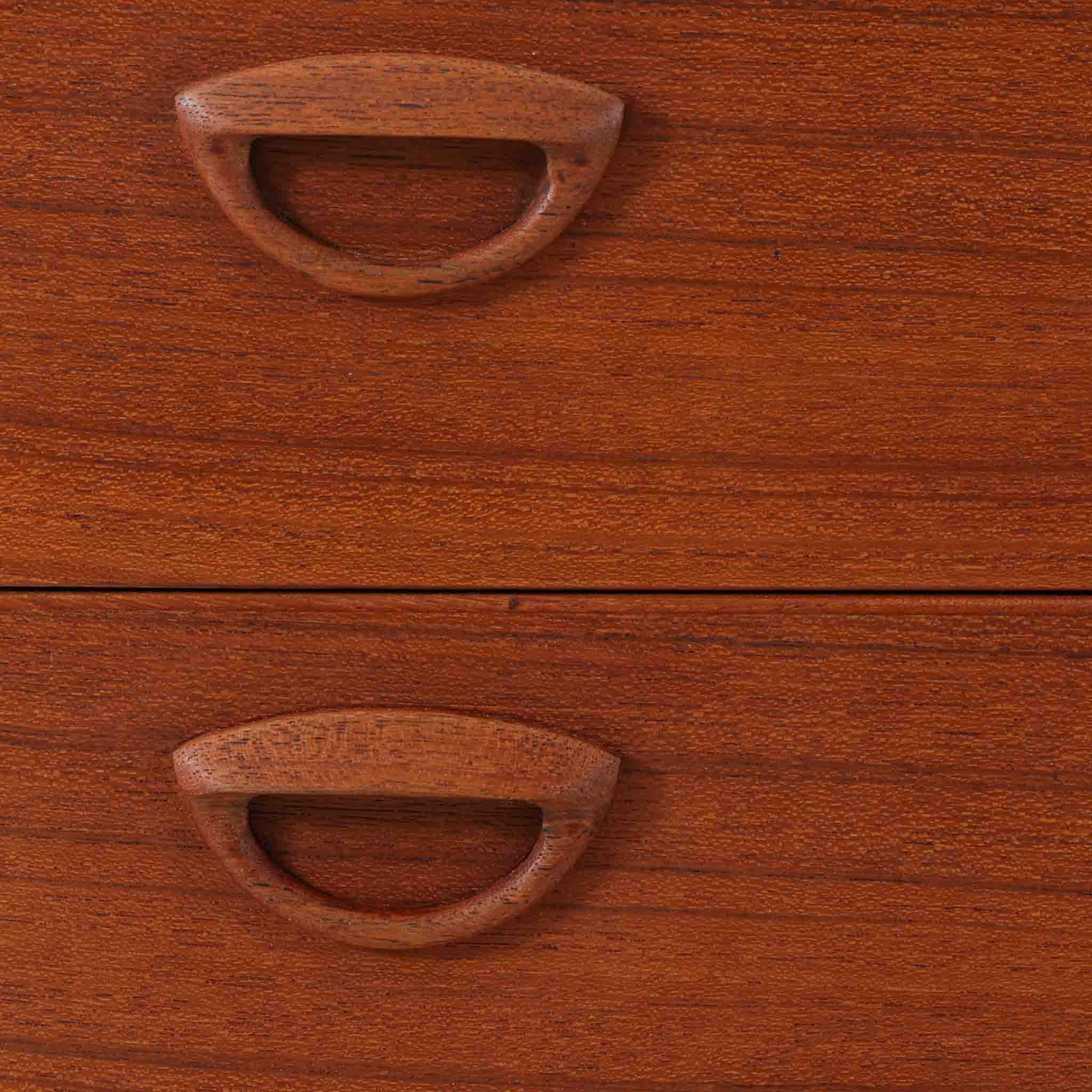 カイ・クリスチャンセンが手掛け、フェルドバレス・モーベルファブリック社によって製作された4段チェストは、北欧ビンテージらしい端正な佇まいと高い実用性を兼ね備えた一台です。良質なチーク材を用いた本体は、木目の美しさが前面に表れ、半円状に削り出された取手や細身のテーパードレッグが、全体に軽やかで洗練された印象を与えています。引き出しは深さにゆとりがあり収納力も十分で、衣類や小物の整理に最適です。経年変化によって深みを増したチークの色合いが空間に温もりを添え、リビングや寝室、書斎など幅広いシーンで主役として活躍します。