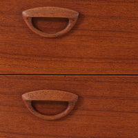 カイ・クリスチャンセンが手掛け、フェルドバレス・モーベルファブリック社によって製作された4段チェストは、北欧ビンテージらしい端正な佇まいと高い実用性を兼ね備えた一台です。良質なチーク材を用いた本体は、木目の美しさが前面に表れ、半円状に削り出された取手や細身のテーパードレッグが、全体に軽やかで洗練された印象を与えています。引き出しは深さにゆとりがあり収納力も十分で、衣類や小物の整理に最適です。経年変化によって深みを増したチークの色合いが空間に温もりを添え、リビングや寝室、書斎など幅広いシーンで主役として活躍します。