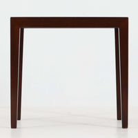 Severin Hansen Jr.（セヴェリン・ハンセン）がデザインし、Haslev社より製造されたタイルトップテーブルで、天板にはNils ThorssonによるBACAシリーズの陶板が贅沢にあしらわれています。端正な角脚を持つマホガニー材のフレームは、ハンセンらしいシャープなジョイントが際立ち、凛とした佇まいを演出します。耐熱性に優れたタイルは日常使いに適しており、サイドテーブルや植物のディスプレイスペースとしても活躍。経年により深みを増した木肌とBACA特有の芸術性が空間に上質なアクセントを添えるビンテージ品です。