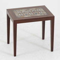 Severin Hansen Jr.（セヴェリン・ハンセン）がデザインし、Haslev社より製造されたタイルトップテーブルで、天板にはNils ThorssonによるBACAシリーズの陶板が贅沢にあしらわれています。端正な角脚を持つマホガニー材のフレームは、ハンセンらしいシャープなジョイントが際立ち、凛とした佇まいを演出します。耐熱性に優れたタイルは日常使いに適しており、サイドテーブルや植物のディスプレイスペースとしても活躍。経年により深みを増した木肌とBACA特有の芸術性が空間に上質なアクセントを添えるビンテージ品です。