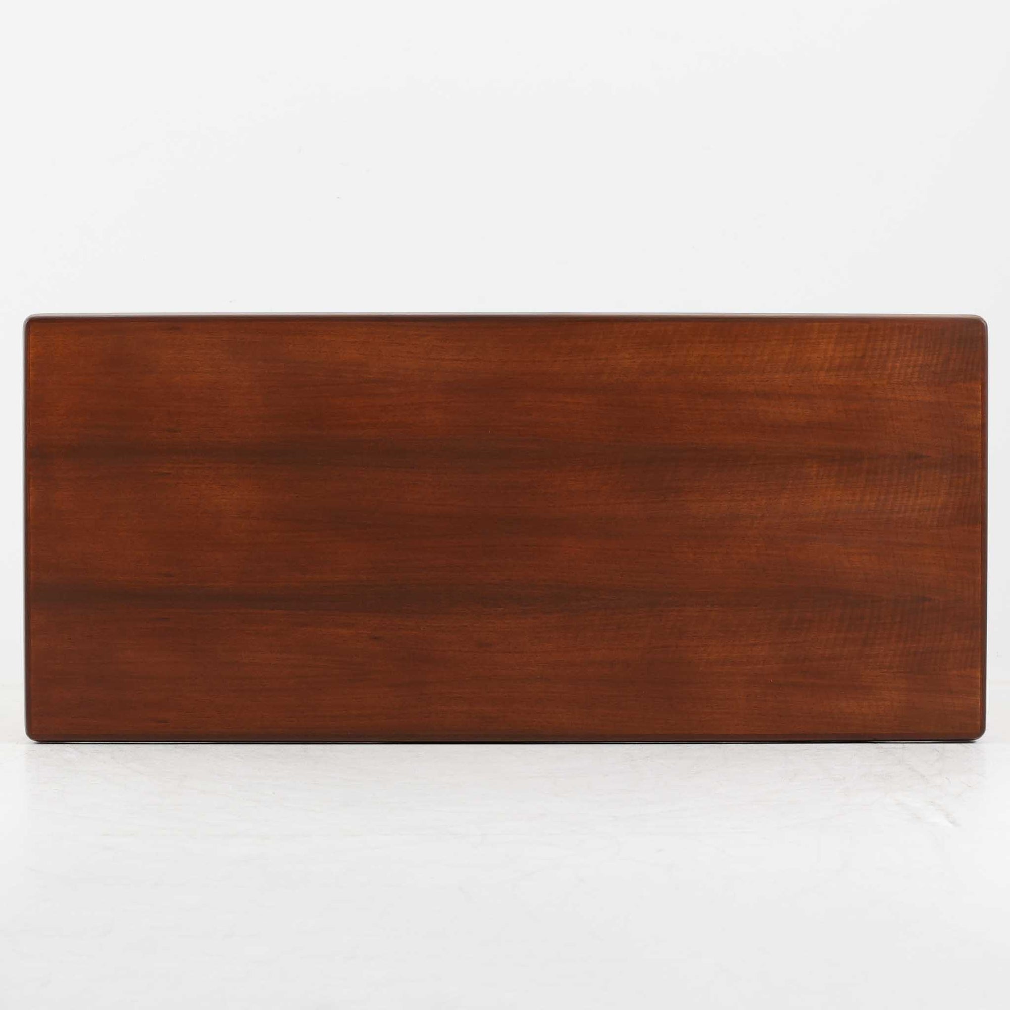 Henning Kjaernulf（ヘニング・ケアヌルフ）によるデザイン、Vejle Stole og Mobelfabrik社製のセンターテーブルです。チーク材特有の深みある色合いと美しい木目が際立ち、北欧家具らしい上質な雰囲気を漂わせます。脚部から幕板にかけての滑らかな曲線が職人技を感じさせ、どの角度から見ても整った美しいフォルムが魅力です。リビングの中心で穏やかな存在感を放ち、ソファとの相性も抜群。経年により増した艶が、ビンテージ家具ならではの温もりを感じさせます。なお、天板や幕板はチーク材と思われ、脚部にはチークに近い色調と質感をもつアフロモシア材が使用されている可能性があります。