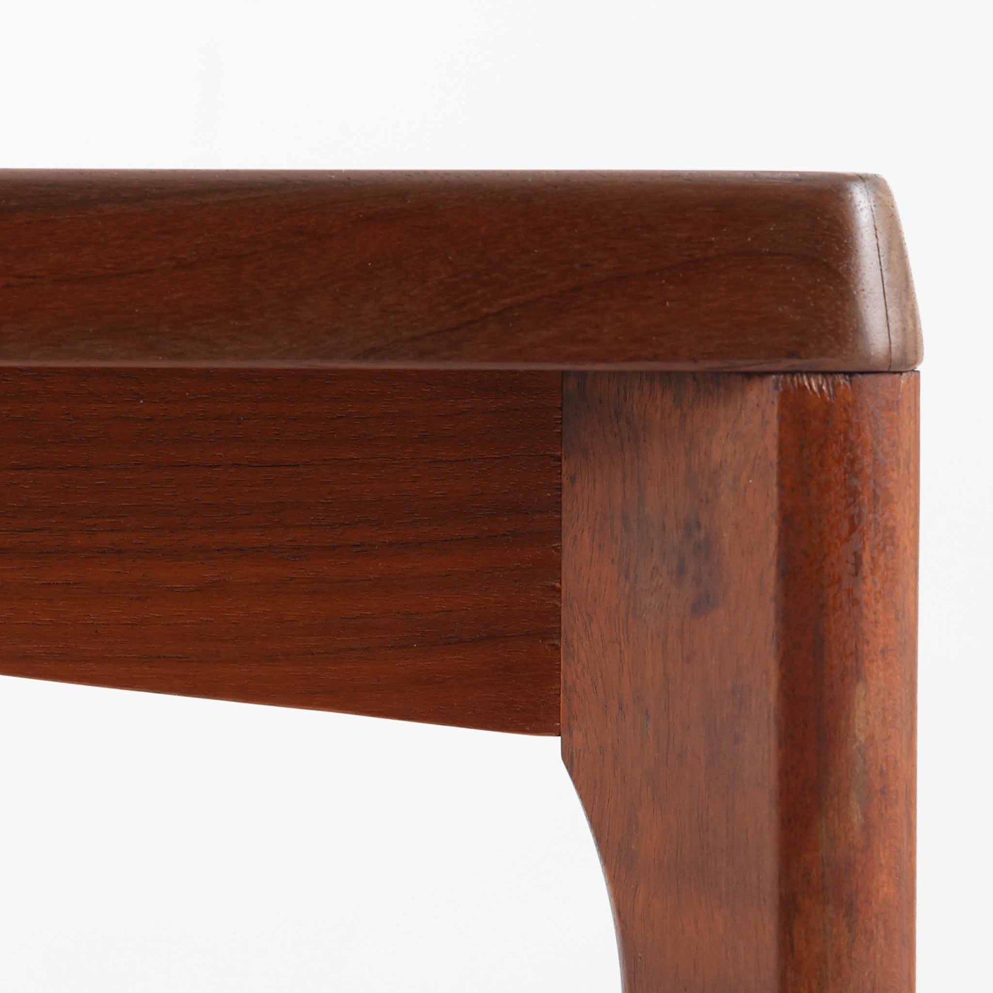 Henning Kjaernulf（ヘニング・ケアヌルフ）によるデザイン、Vejle Stole og Mobelfabrik社製のセンターテーブルです。チーク材特有の深みある色合いと美しい木目が際立ち、北欧家具らしい上質な雰囲気を漂わせます。脚部から幕板にかけての滑らかな曲線が職人技を感じさせ、どの角度から見ても整った美しいフォルムが魅力です。リビングの中心で穏やかな存在感を放ち、ソファとの相性も抜群。経年により増した艶が、ビンテージ家具ならではの温もりを感じさせます。なお、天板や幕板はチーク材と思われ、脚部にはチークに近い色調と質感をもつアフロモシア材が使用されている可能性があります。