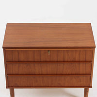 デンマーク製のチーク材3段チェストです。前板の一体的なデザインが美しく、取手部分を削り出した滑らかなラインが上品な印象を与えます。幅が77cmと少し大きめで、コンパクトながら収納力があり、寝室や玄関、リビングのサイド収納としても活躍します。最上段には鍵付きの引き出しが設けられ、大切な書類や貴重品の保管にも便利です。脚部まで丁寧に仕上げられた造りは北欧家具ならではの職人技を感じさせ、空間に温もりを添えてくれます。