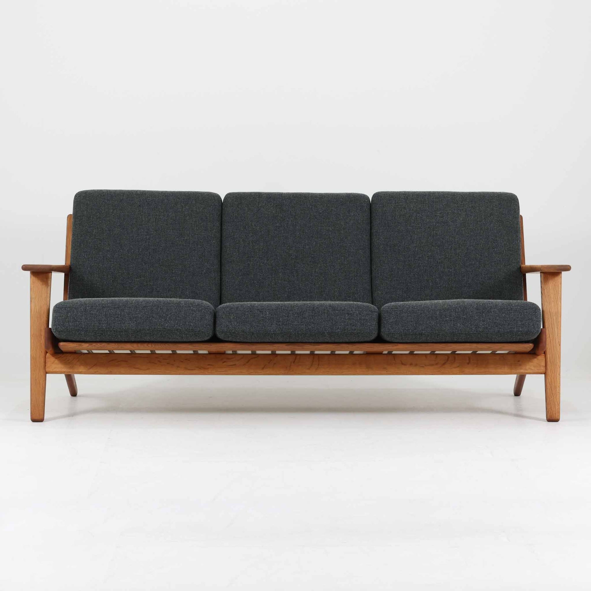 Hans J. Wegnerがデザインし、Getamaより製造された名作ソファ「GE290」です。オーク材の美しい木目を活かした堅牢なフレームと、背面まで美しく仕上げられたスポーク構造が特徴で、空間の中央にも映える洗練された佇まいを備えています。ゆったりとした3人掛けの座面は快適な掛け心地を実現し、リビングの主役として長く愛用できる一台。時代を超えて評価されるウェグナーならではの機能美と、ビンテージならではの味わい深い経年変化を存分に楽しめる北欧家具です。