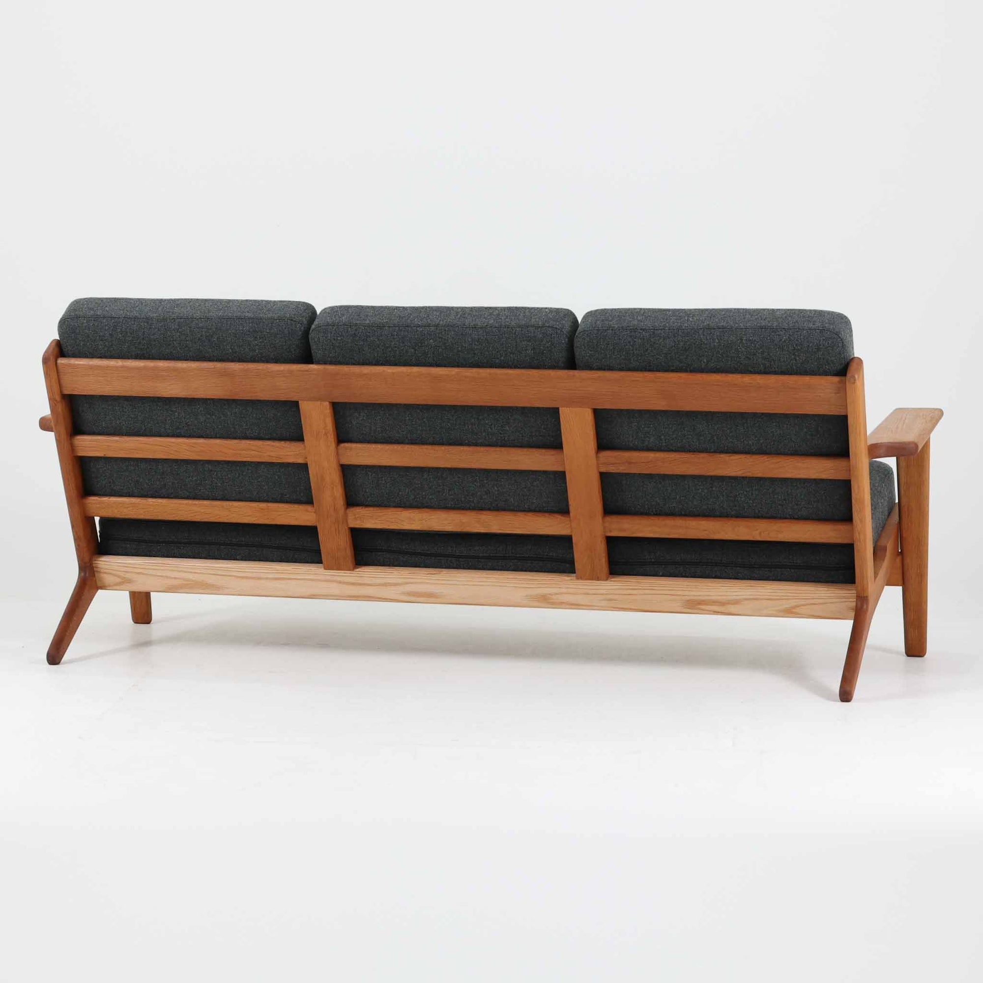 Hans J. Wegnerがデザインし、Getamaより製造された名作ソファ「GE290」です。オーク材の美しい木目を活かした堅牢なフレームと、背面まで美しく仕上げられたスポーク構造が特徴で、空間の中央にも映える洗練された佇まいを備えています。ゆったりとした3人掛けの座面は快適な掛け心地を実現し、リビングの主役として長く愛用できる一台。時代を超えて評価されるウェグナーならではの機能美と、ビンテージならではの味わい深い経年変化を存分に楽しめる北欧家具です。